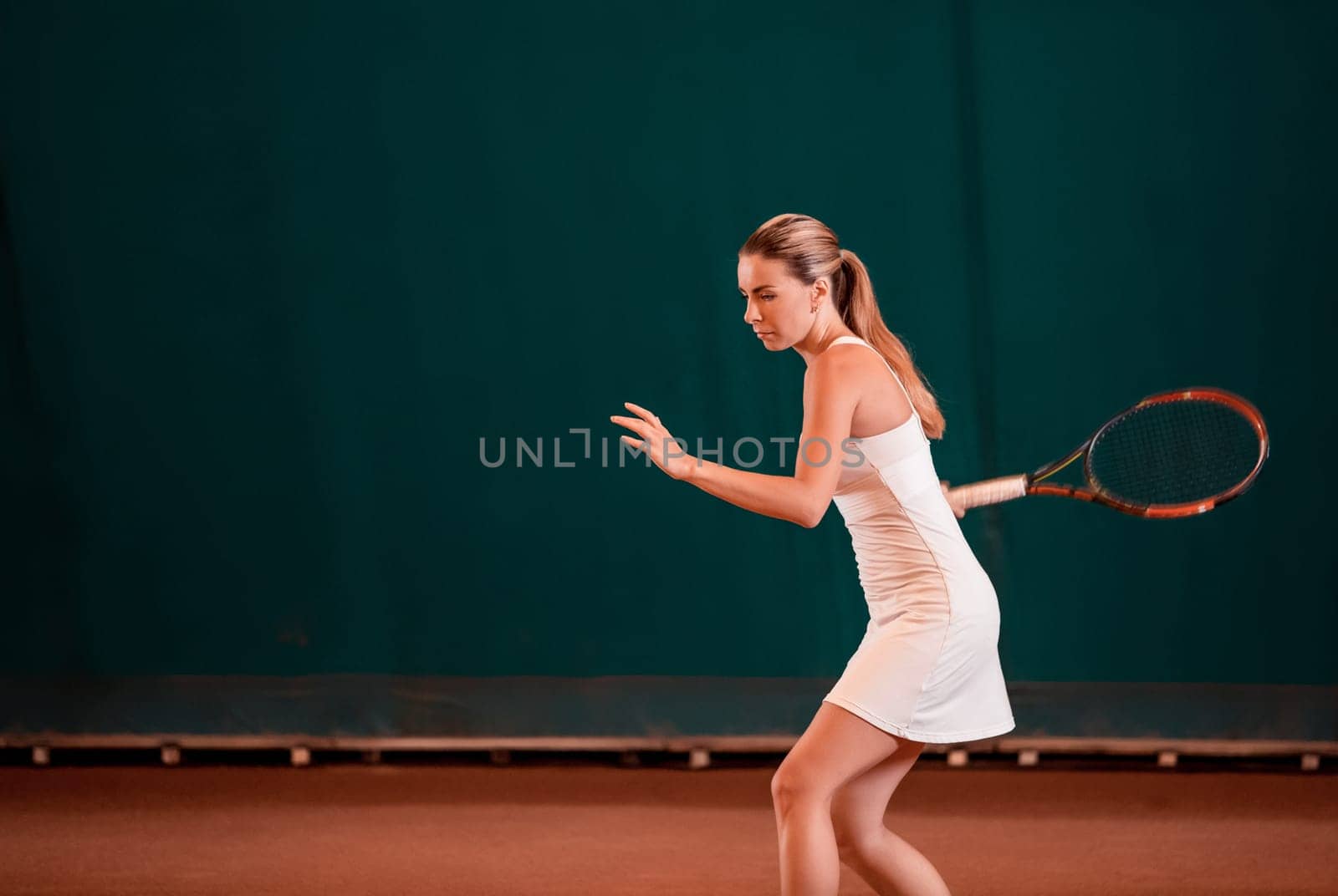 Indoor tennis court playing athlete. Young woman playing tennis