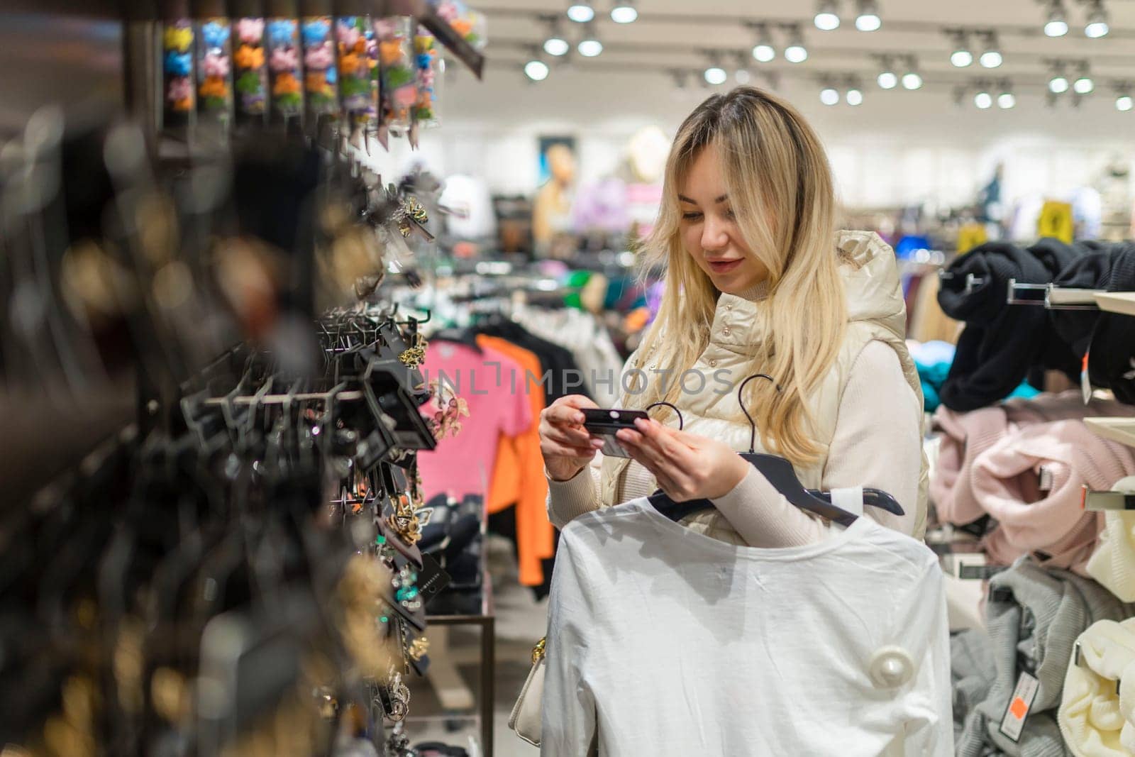 Happy girl on sale in a clothing store chooses jewelry by malyshph