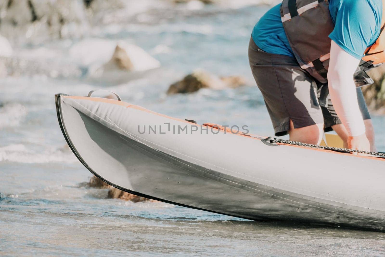 Happy couple kayaks in an inflatable kayak on the sea at sunset. Couple kanoeing in the sea near the island with mountains. People kayaking in life jackets sail. Back view by panophotograph