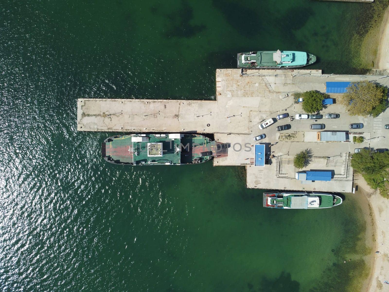 Ferry boat crossing the sea, carrying cars and passengers. Cars drive off the deck onto the port. Top-down aerial drone view Ferry on the lake, transporting cars: deck of a boat carrying vehicles. by panophotograph