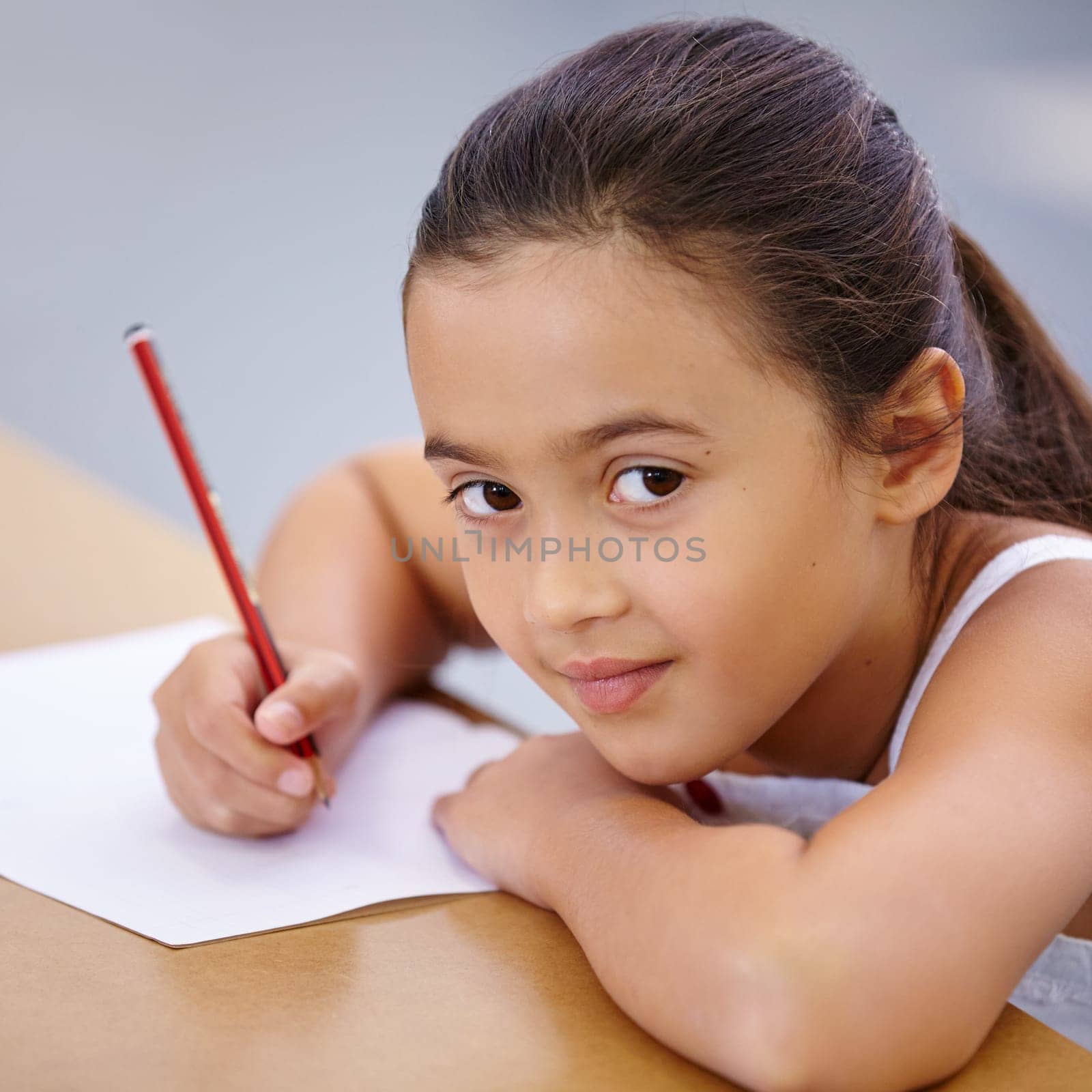 Child, portrait and education of student taking notes in classroom for knowledge and development. Serious, girl and learner writing on paper, studying or learning in middle school class in Spain