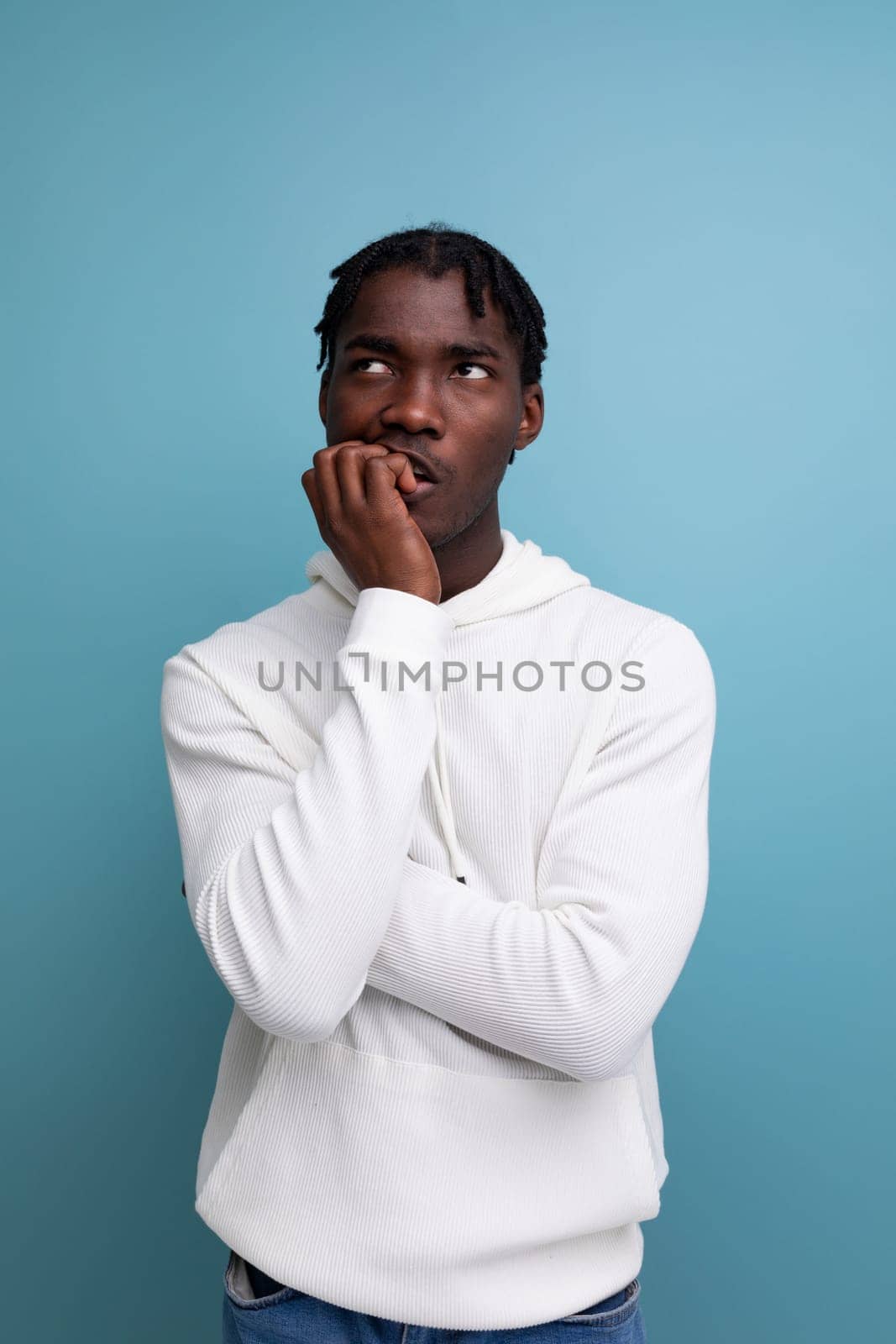 thinking african young brunette man looking at ceiling on studio isolated background.