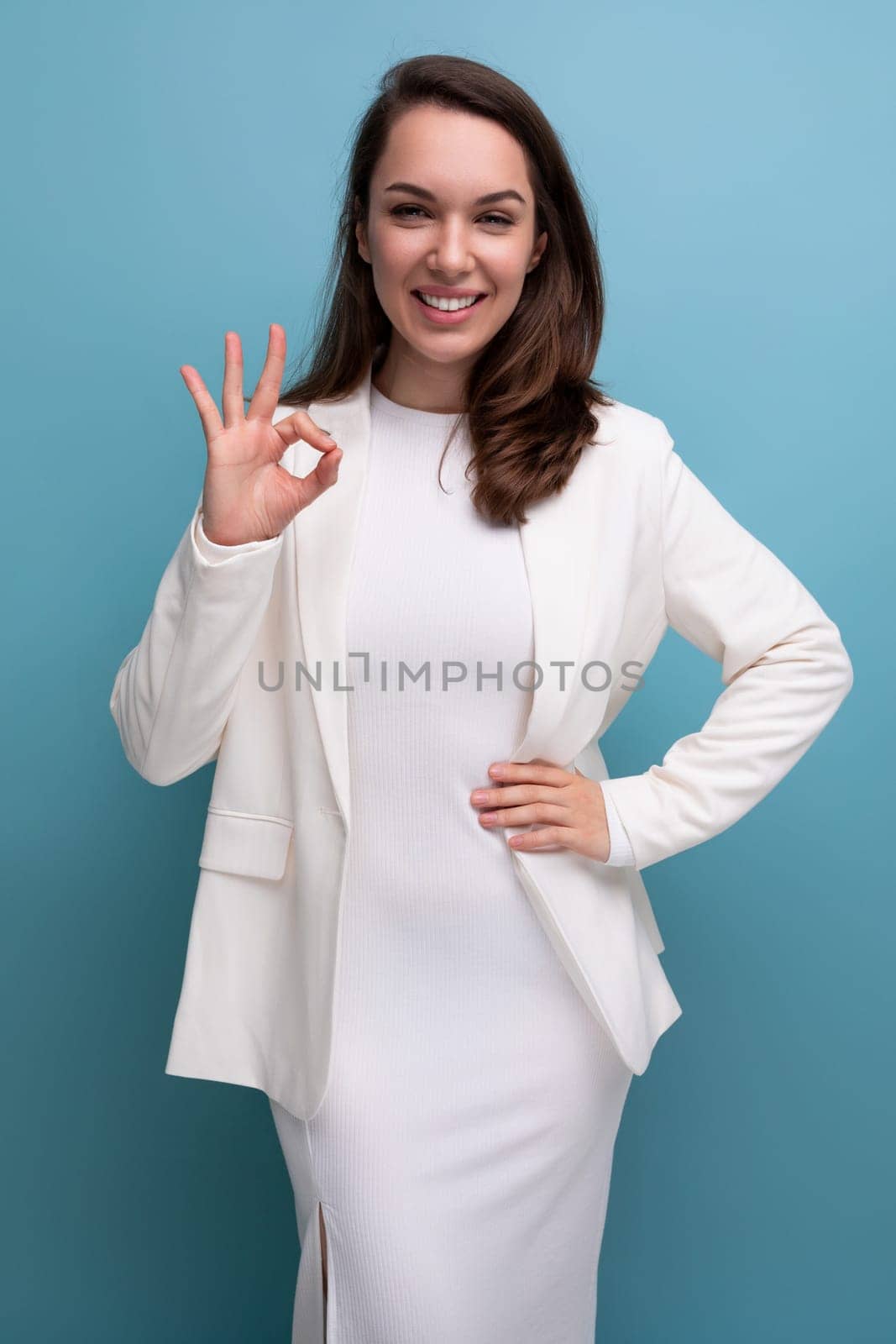 portrait of a well-groomed confident young brunette business woman in a white dress and jacket.