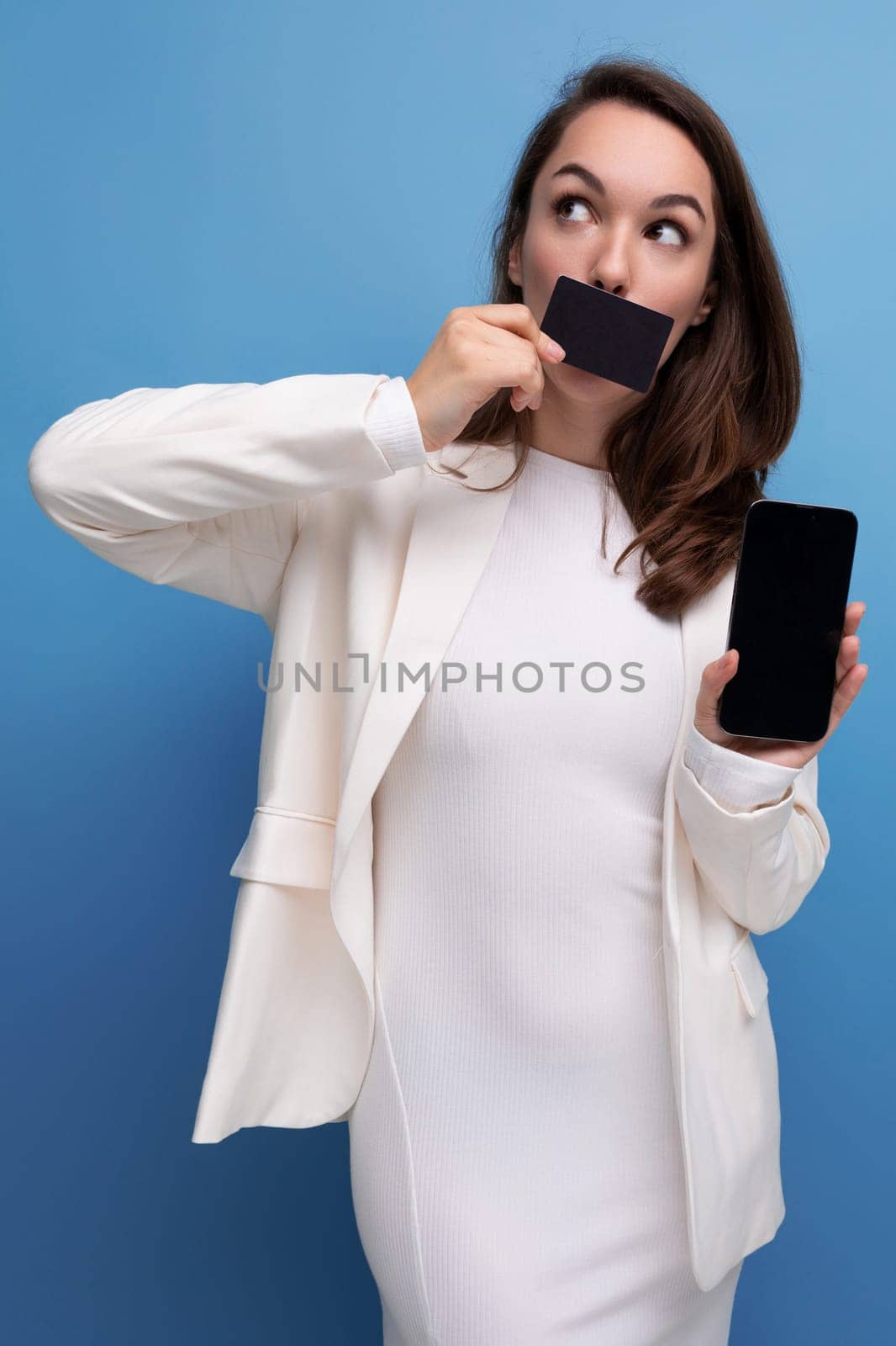 financial worker brunette young woman in a dress and jacket with a payment card for shopping and a smartphone.