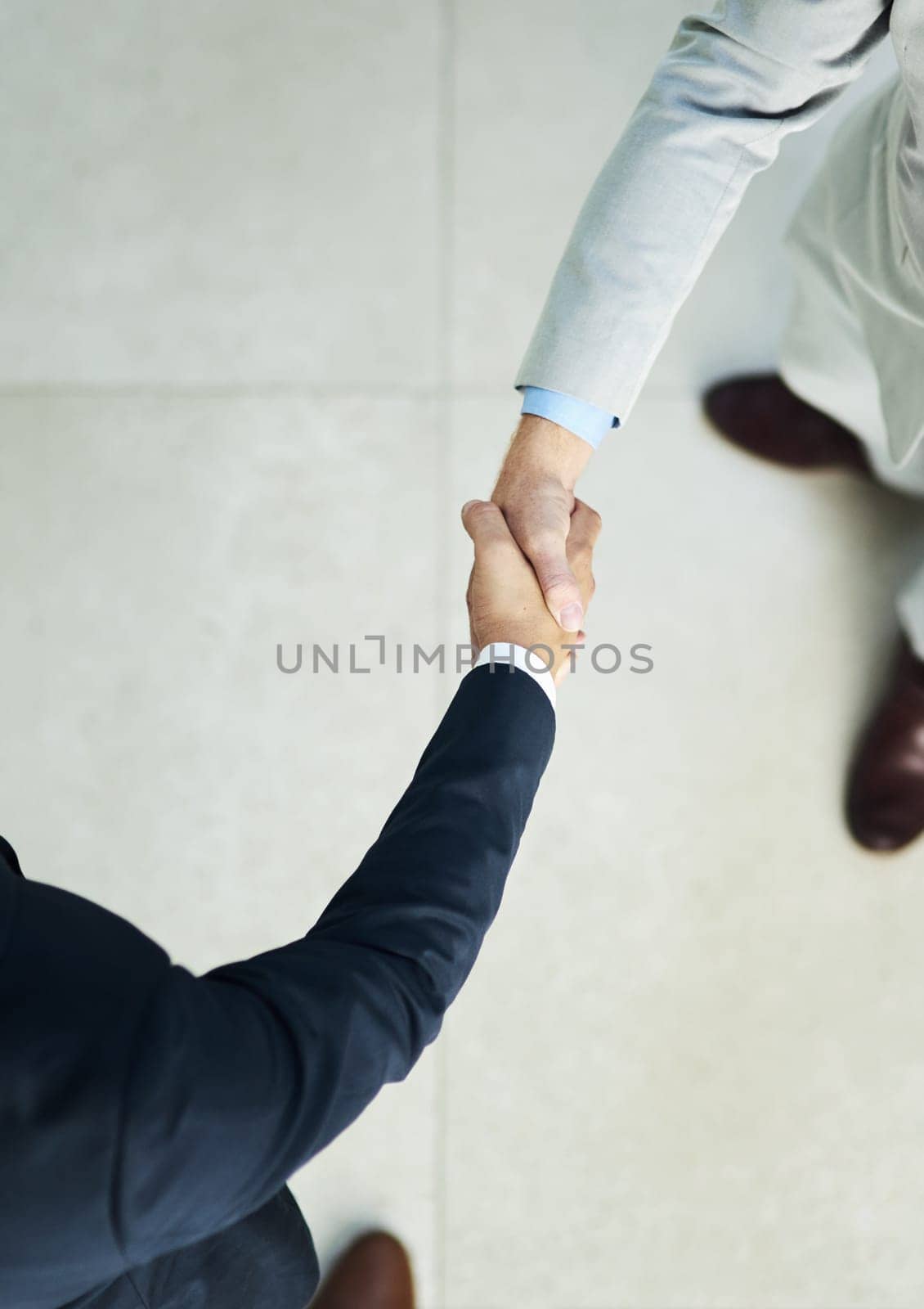 High angle shot of two unidentifiable businessmen shaking hands in the office.