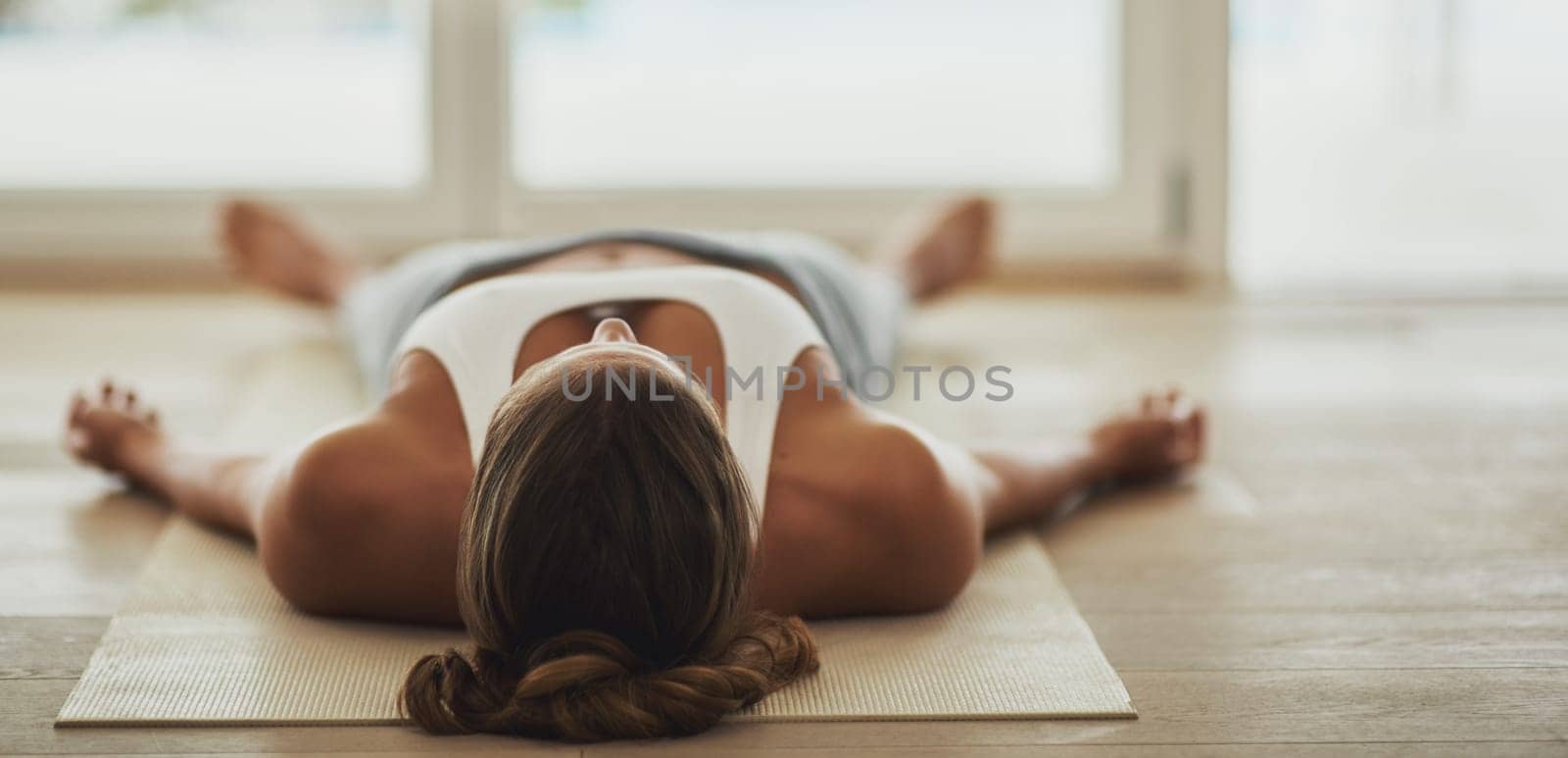 That workout really took it out of her. Shot of a young woman lying on her yoga mat after a workout. by YuriArcurs