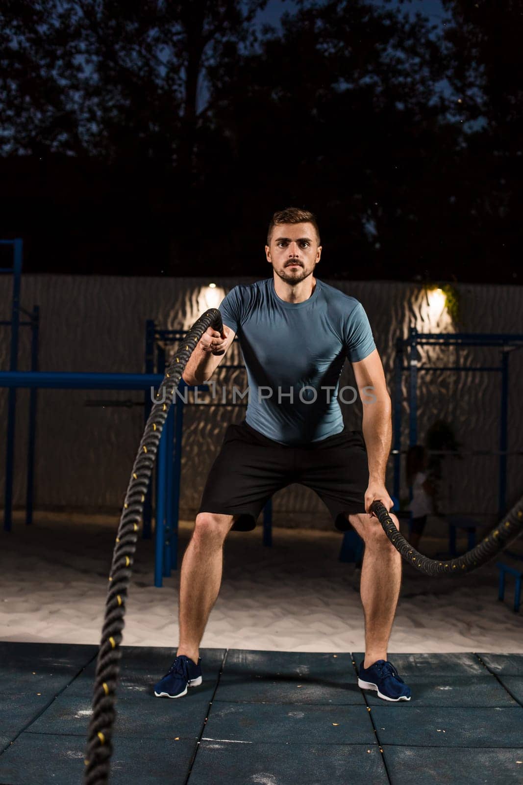 Young man in sportswear training with ropes. Athlete Outdoors