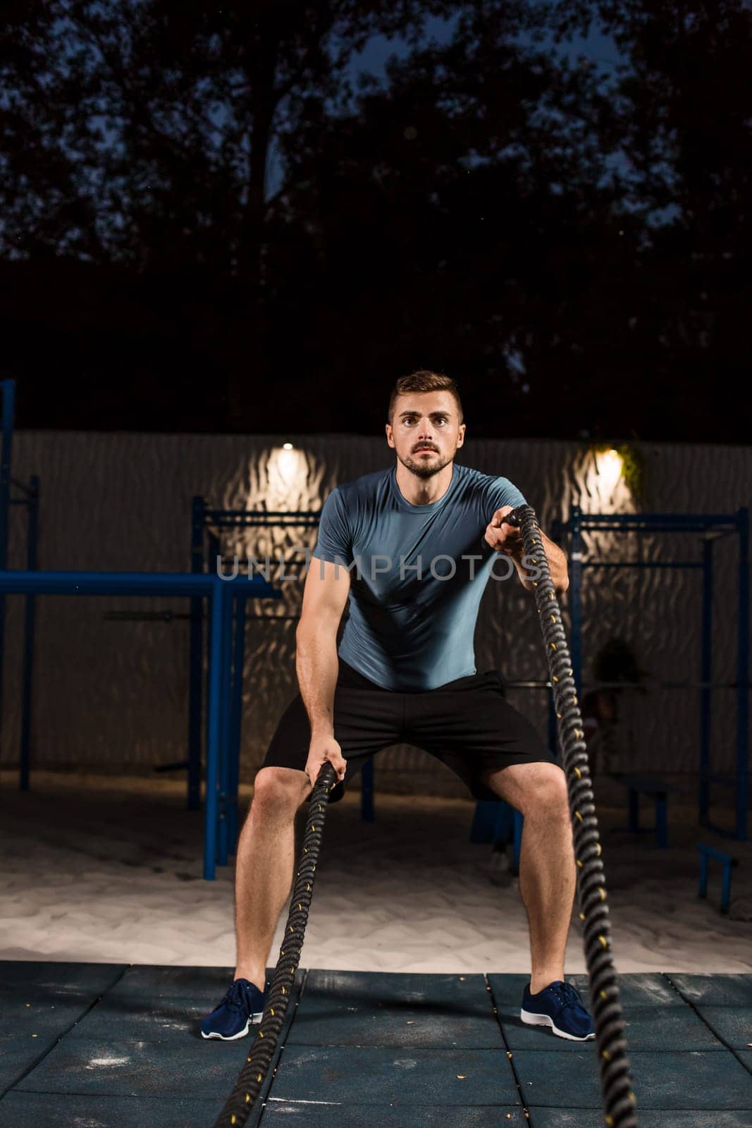 Young man in sportswear training with ropes. Athlete Outdoors