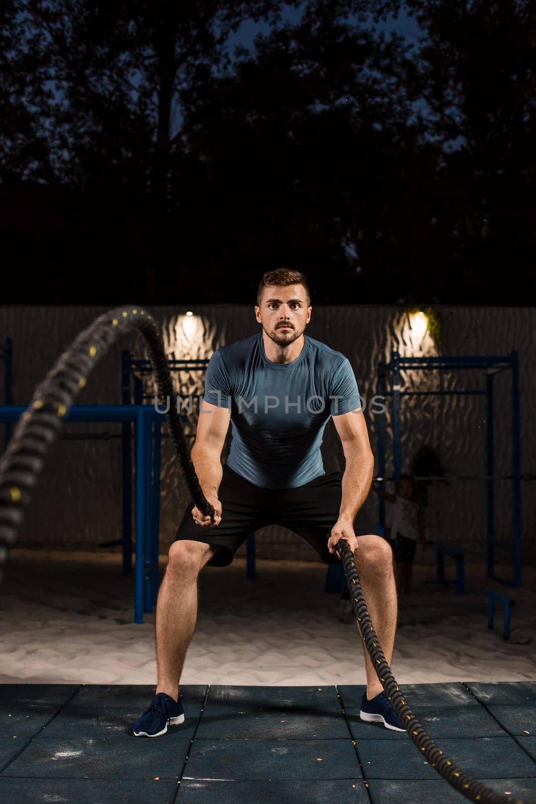 Young man in sportswear training with ropes. Athlete Outdoors