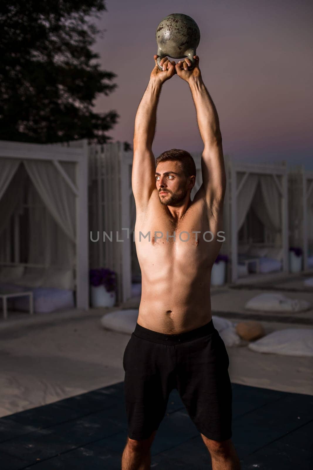 Muscular man working with weights at outdoor. sport exercises with kettlebell. street workout