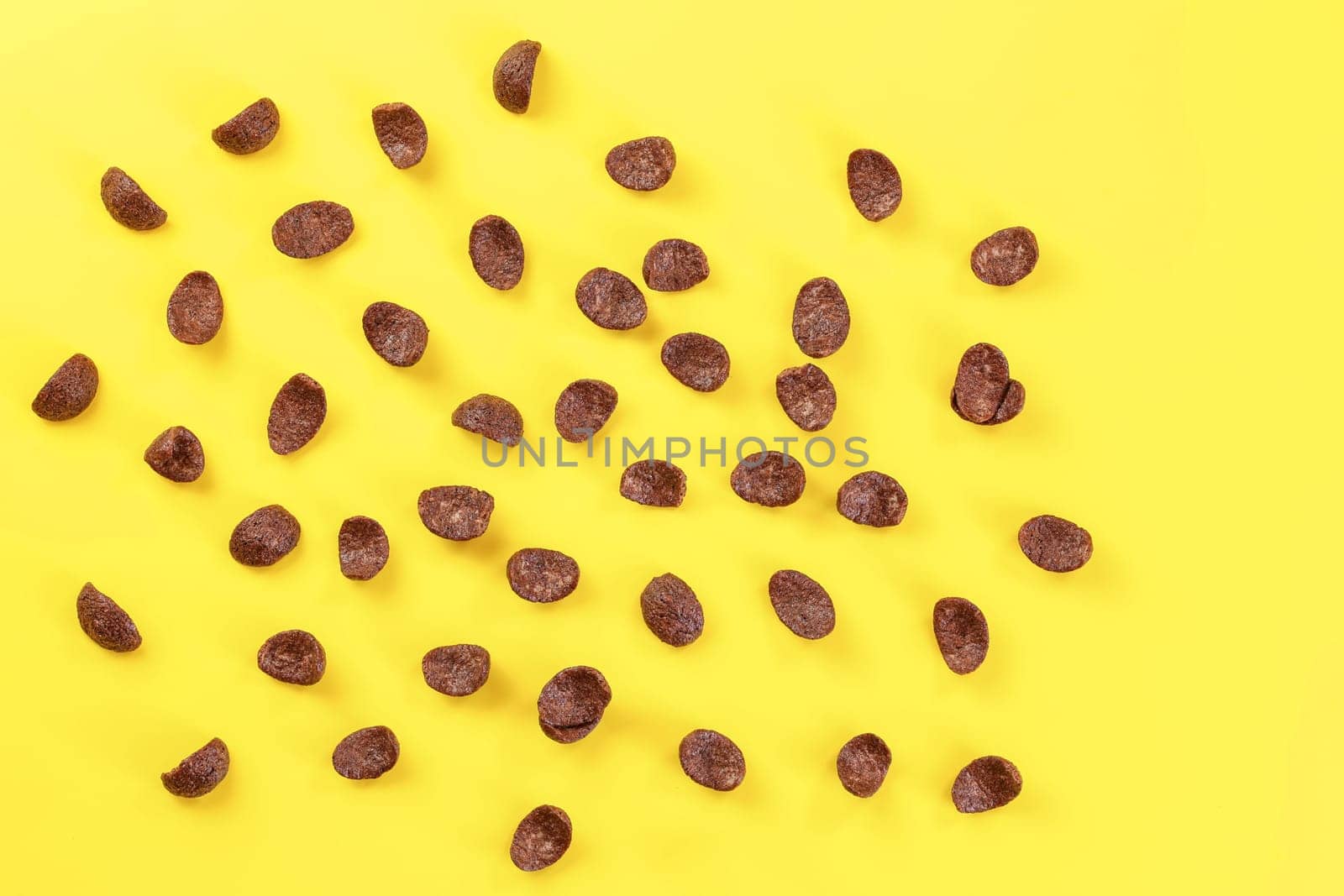 Top down view, chocolate cornflakes scattered on yellow board.