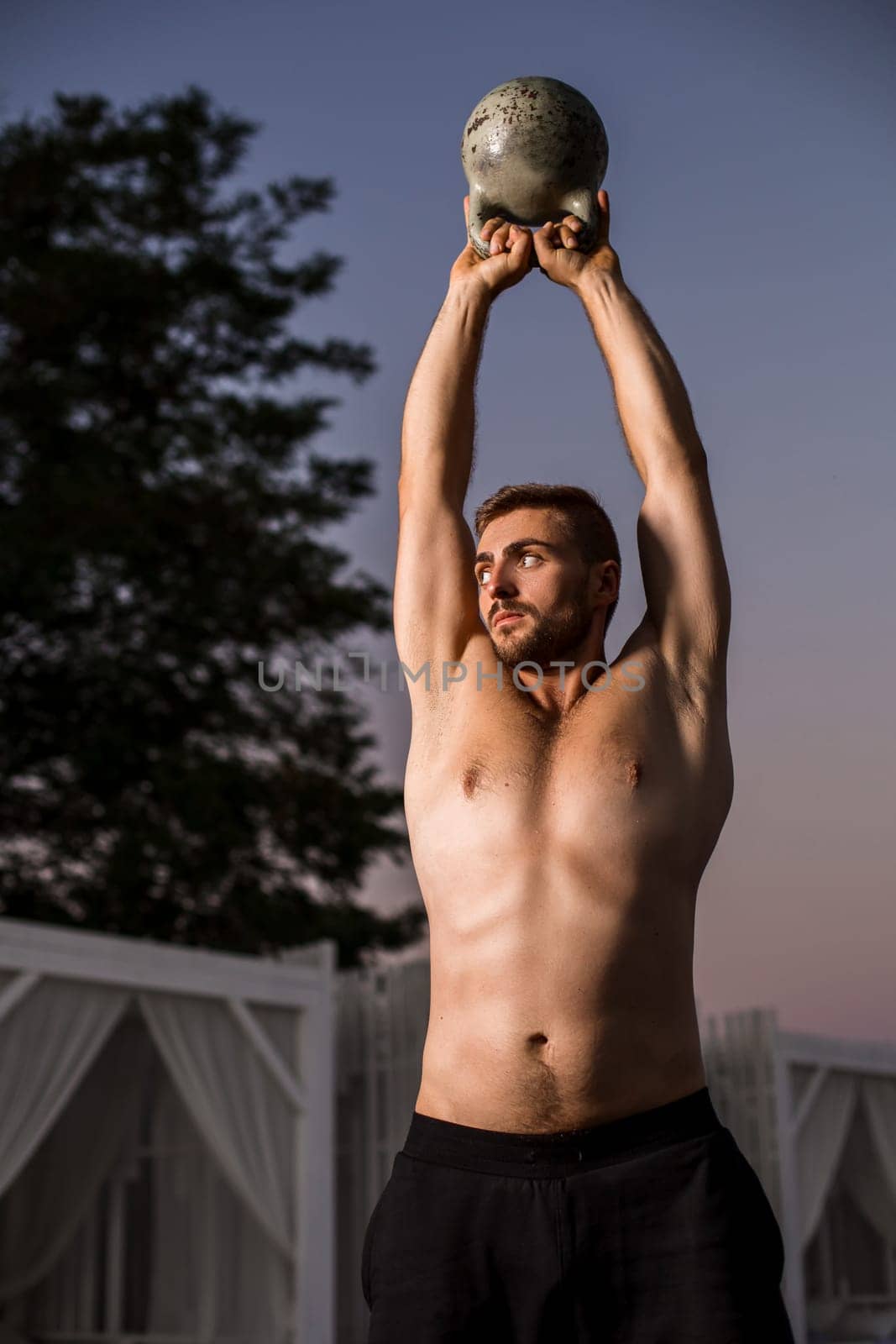 Muscular man working with weights at outdoor. sport exercises with kettlebell. street workout