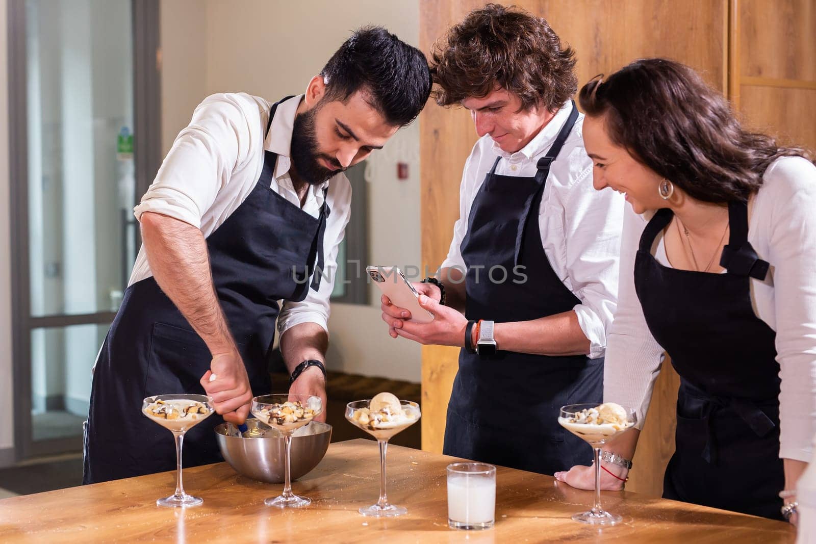 Chef teaching trainees how to make ice cream. Cooking tasty ice cream dessert made from chocolate and vanilla in glass bowl by Satura86