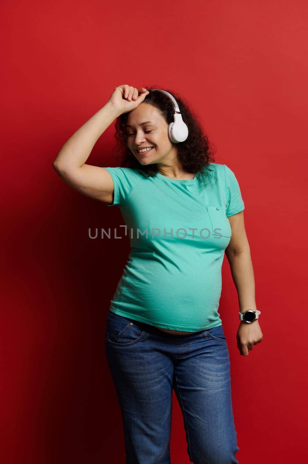 Adult pregnant woman dancing listening to music on headphones, enjoying wonderful moments of happy carefree pregnancy by artgf