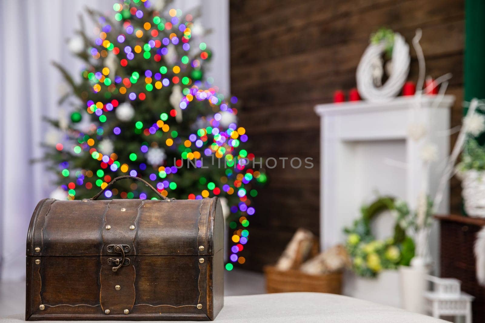 In front you can see an old brown box and against the fuzzy background stands a Christmas tree decorated with glowing Christmas tree lights.