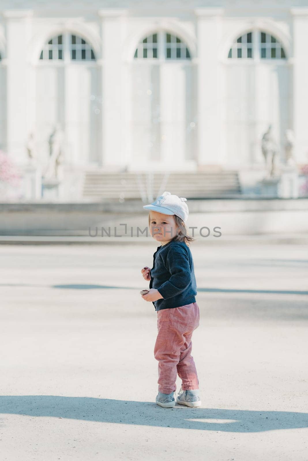 A female toddler with her back in the yard of the European palace. by RomanJRoyce