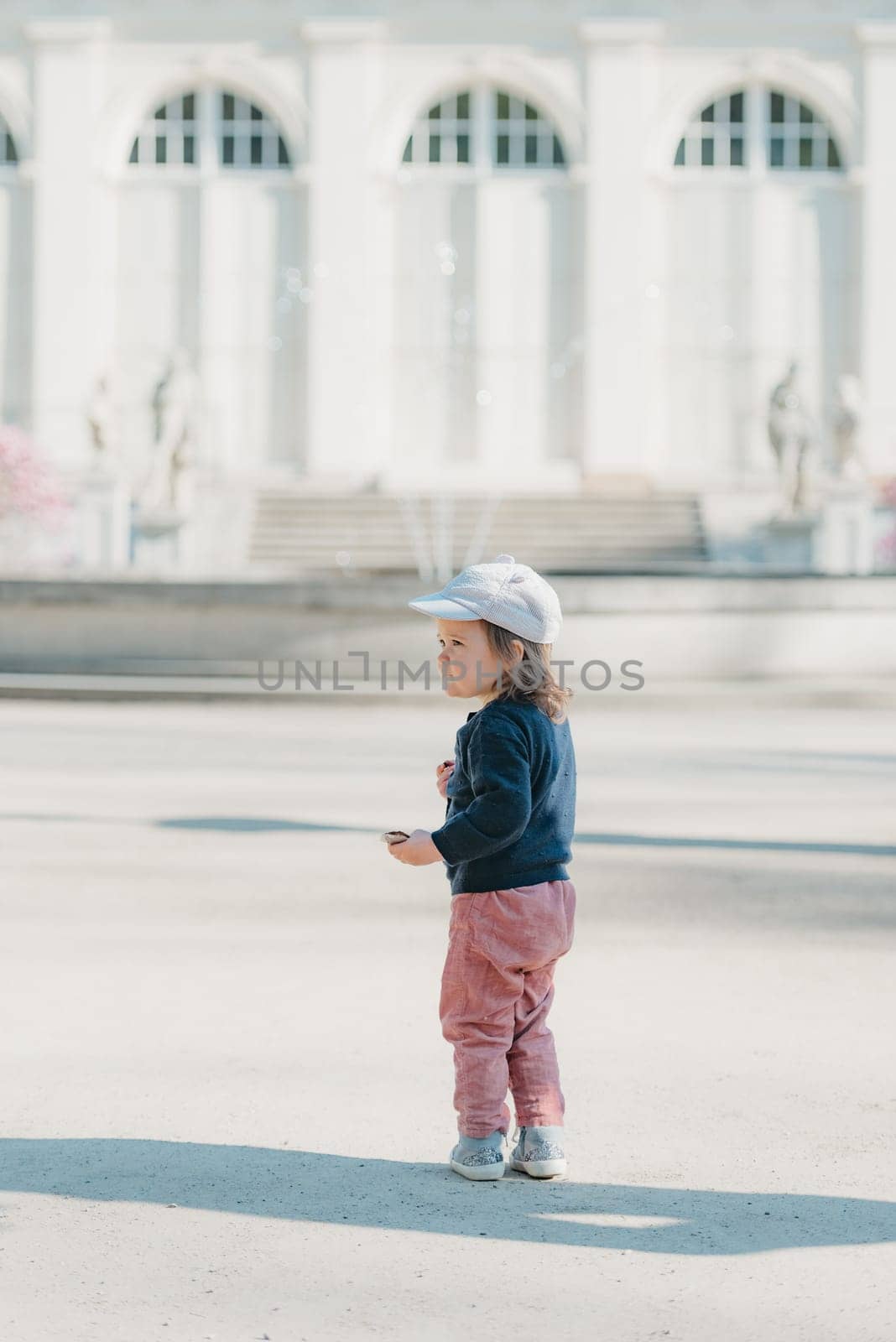 A female toddler with her back in the yard of the European palace. by RomanJRoyce