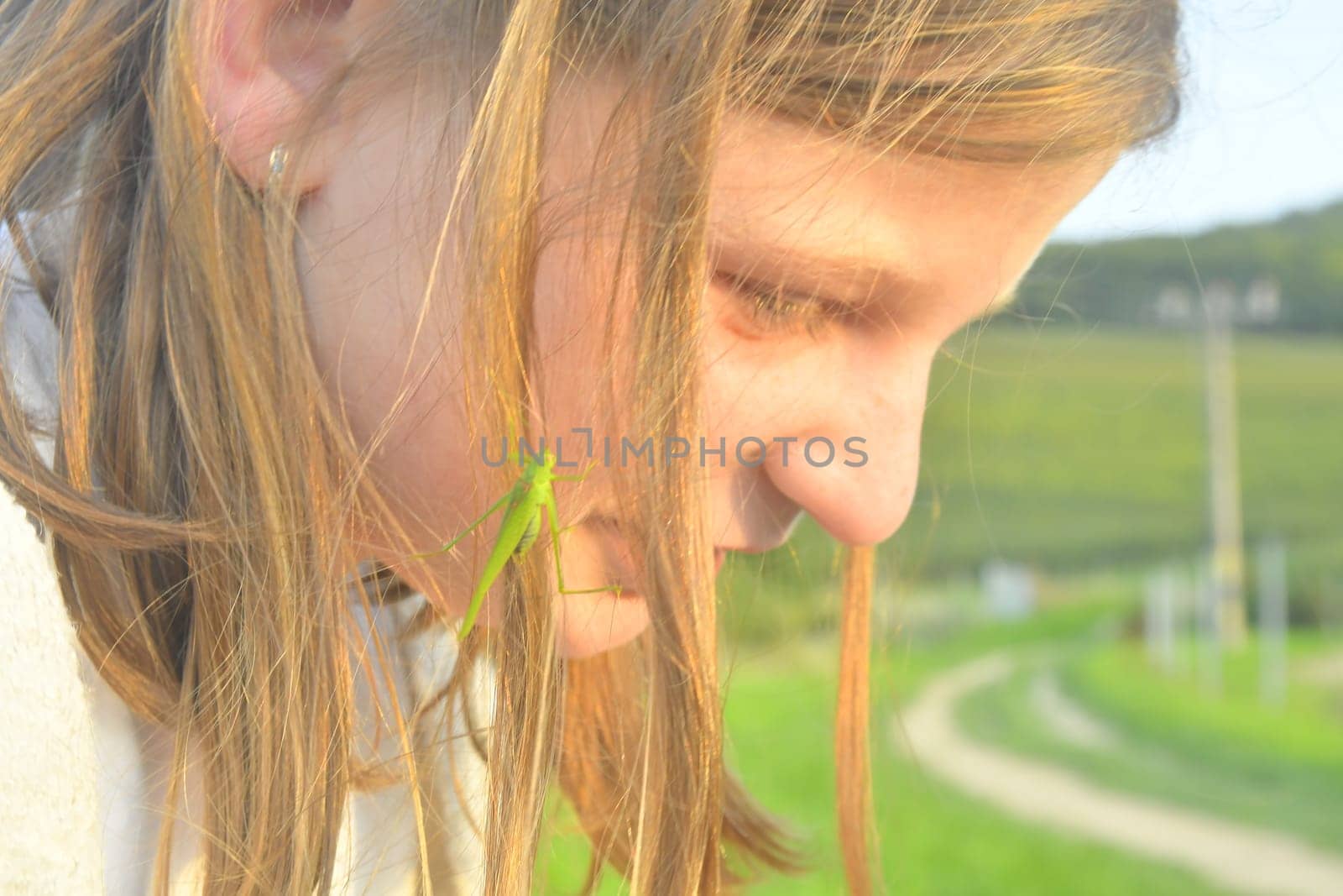 A little blonde girl with a grasshopper in her hair. The concept of romance and carefree childhood. by roman_nerud