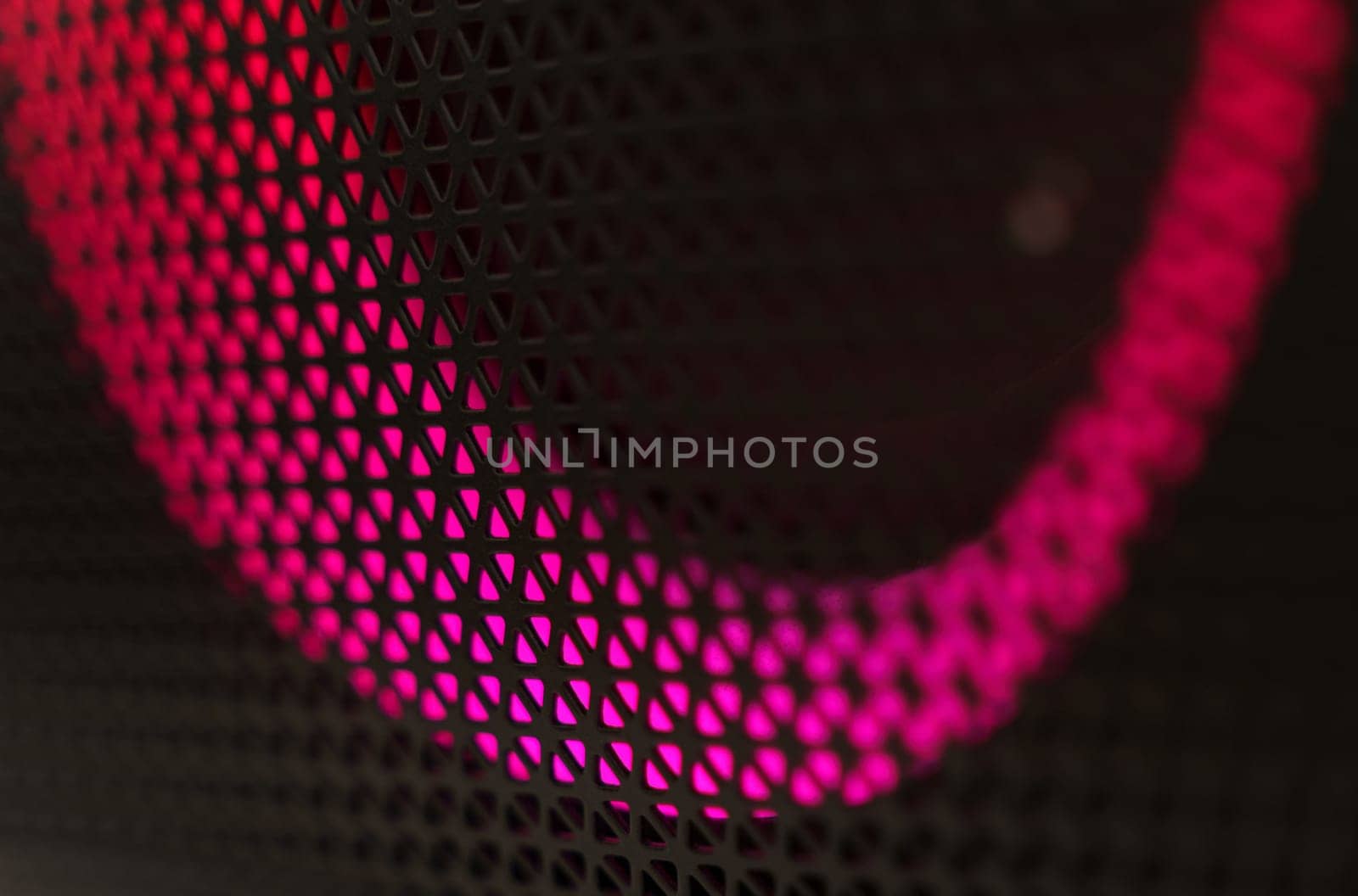 Abstract background of a black patterned lattice behind which glow red LEDs.