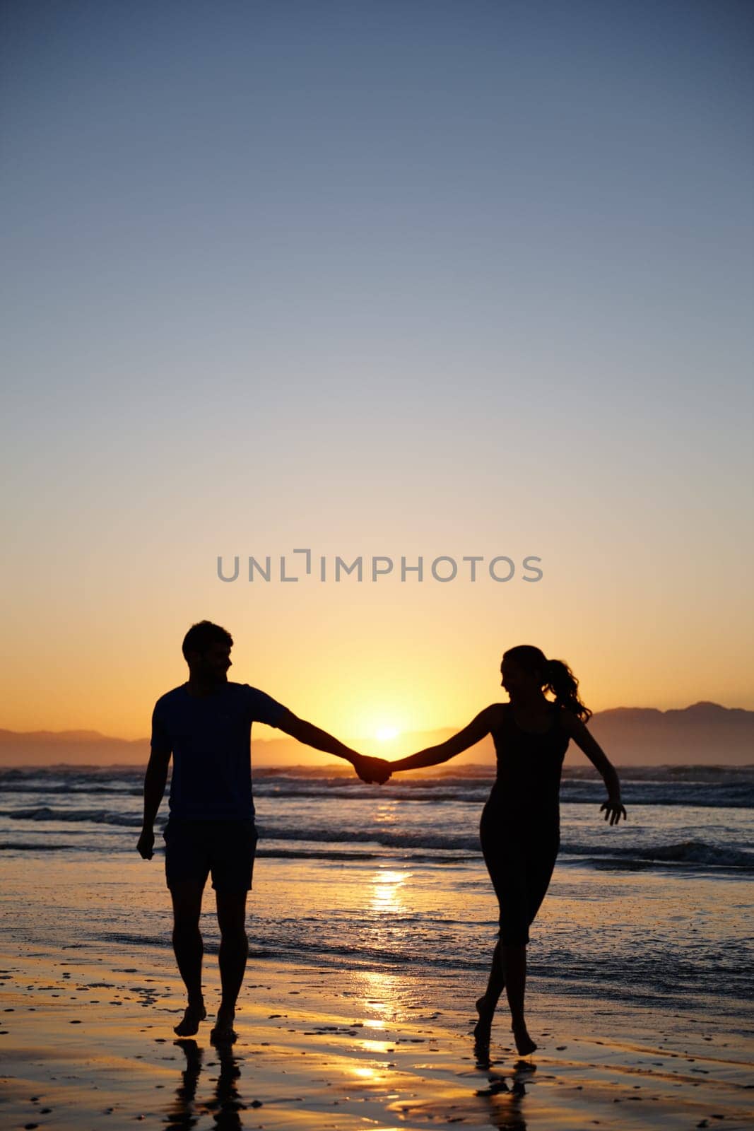 Keeping romance fresh. Silhouette image of a couple holding hands at sunrise. by YuriArcurs