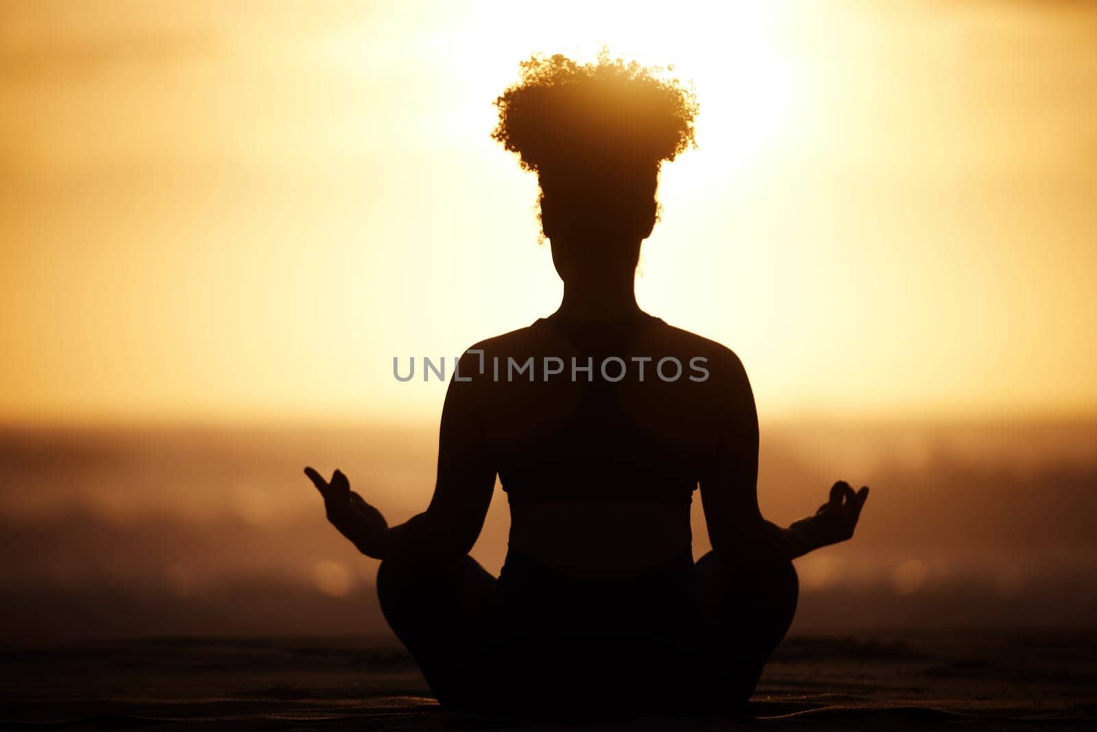 Yoga takes you into the present moment. Shot of a unrecognizable female doing yoga on the beach