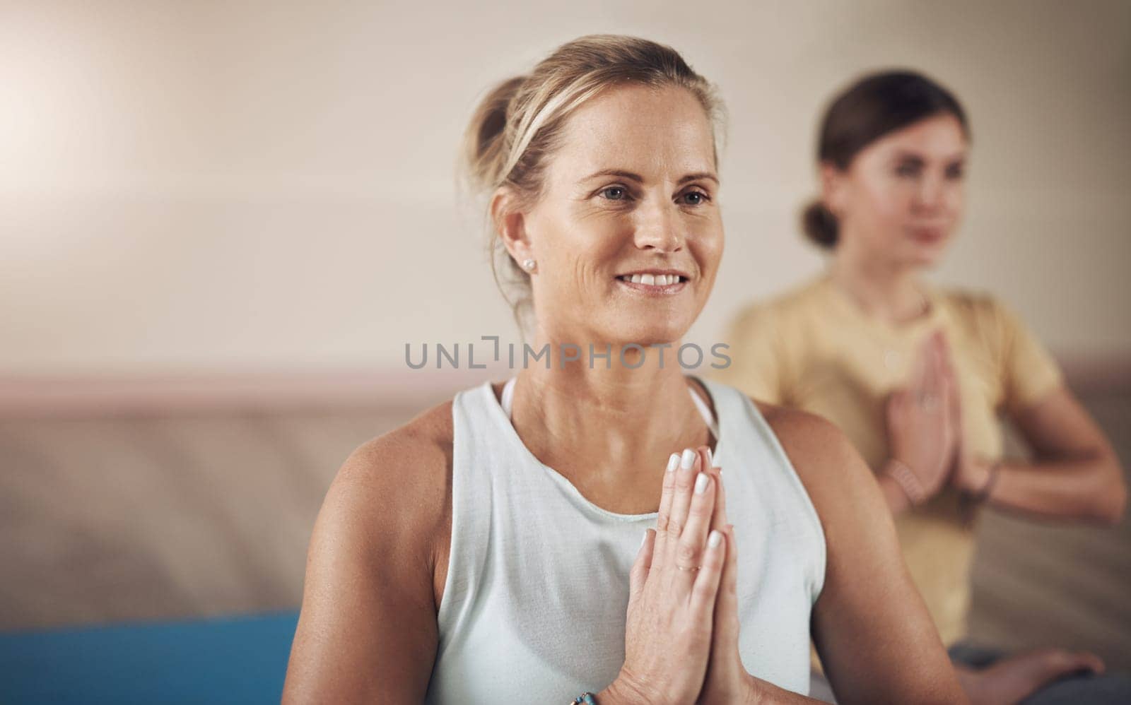 Meditation and yoga go hand in hand. two young women sitting together and meditating with their palms together after an indoor yoga session