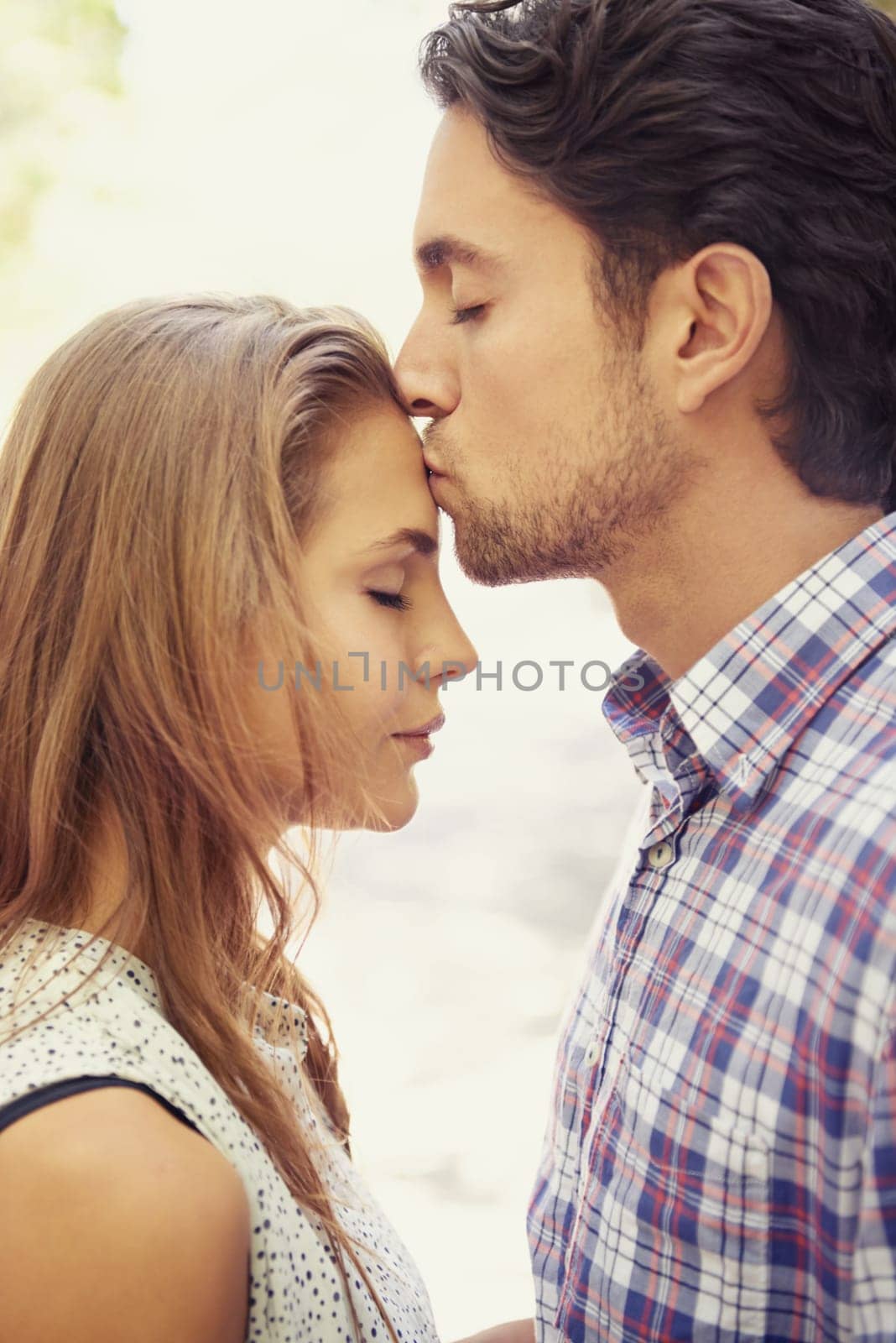 Kiss, affection and couple with love in nature on a date, bonding and loving in a relationship. Content, romance and man kissing a woman on the forehead during valentines day at a park in Italy.