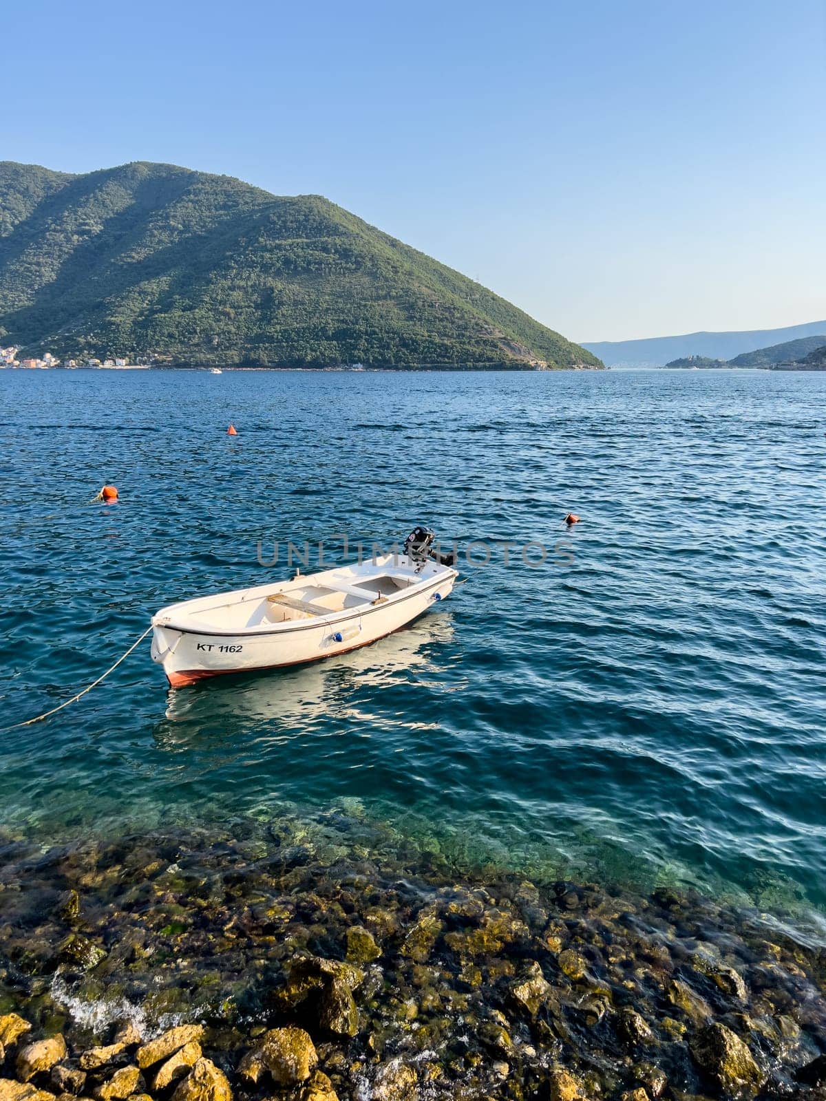 White fishing boat moored on the shallows against the backdrop of the mountains. High quality photo