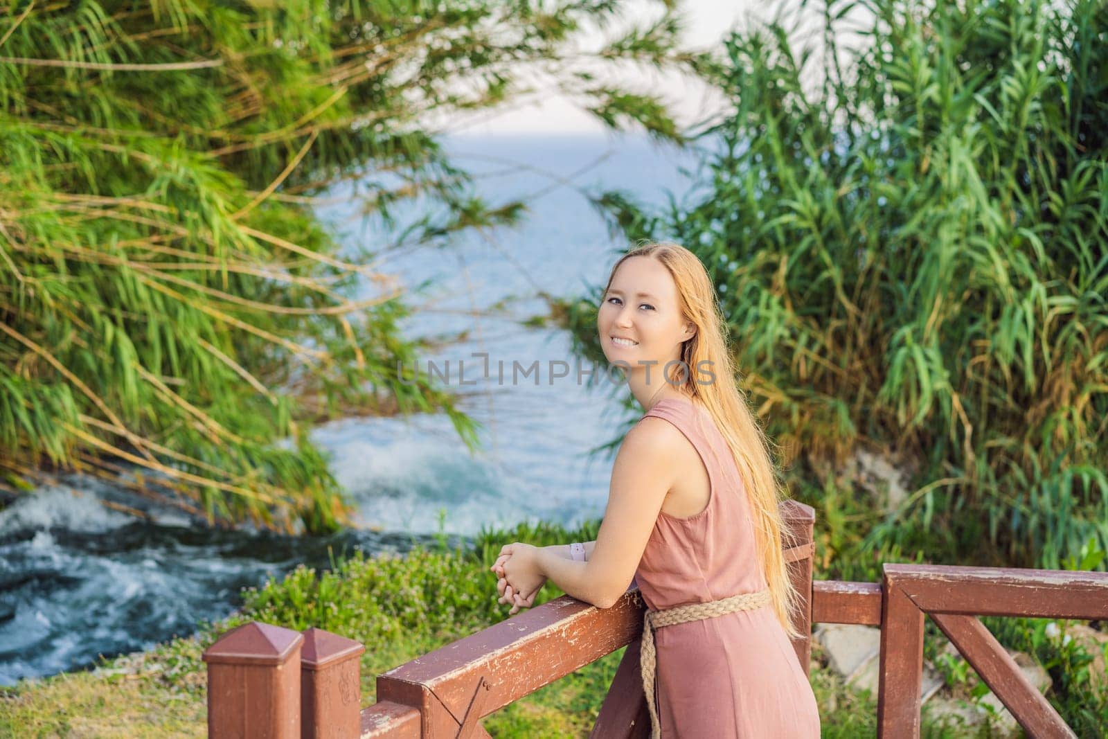 Beautiful woman with long hair on the background of Duden waterfall in Antalya. Famous places of Turkey. Lower Duden Falls drop off a rocky cliff falling from about 40 m into the Mediterranean Sea in amazing water clouds. Tourism and travel destination photo in Antalya, Turkey. Turkiye by galitskaya