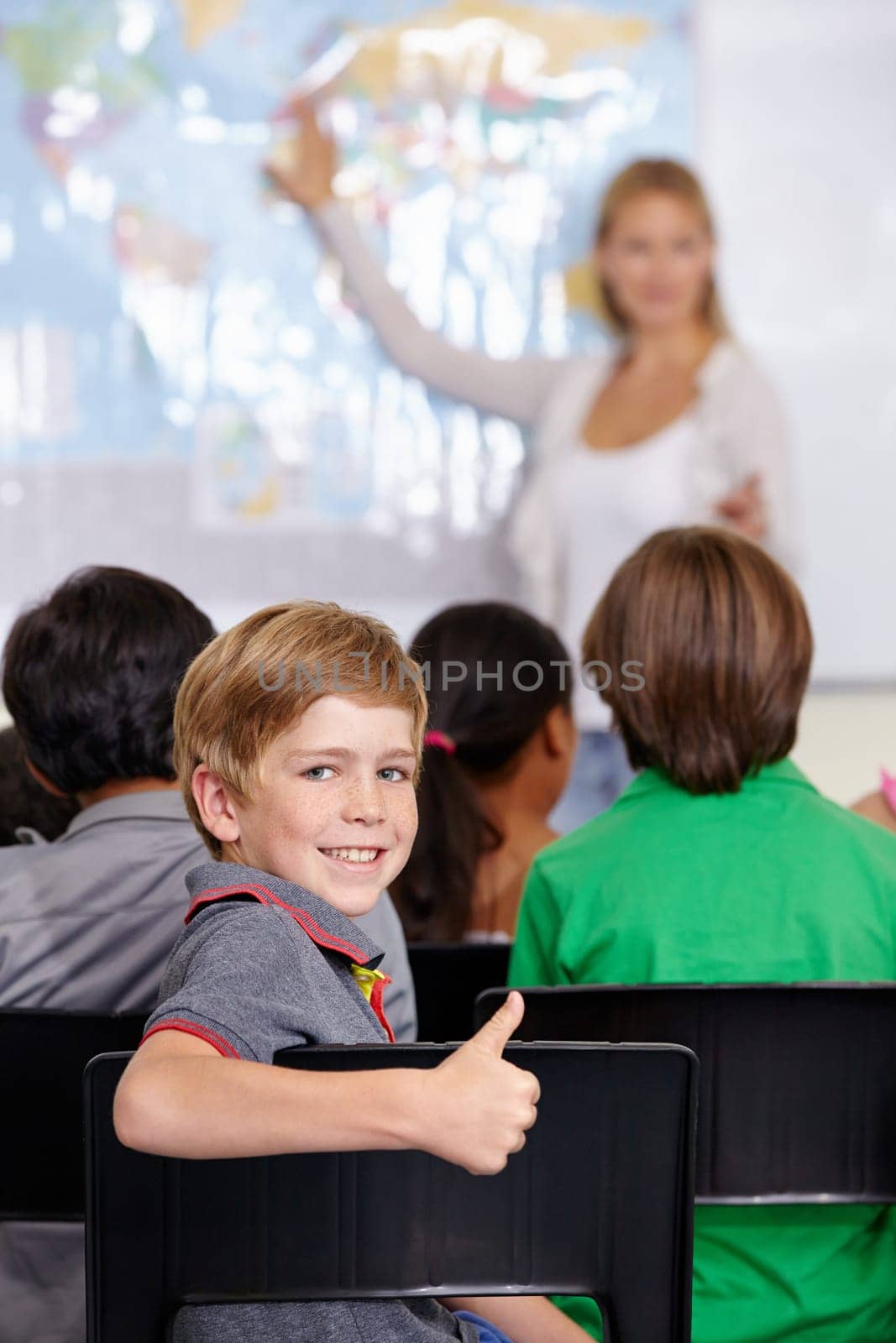 Kid, portrait and thumbs up of student in classroom, elementary school or class. Smile, education and child with hand gesture for like emoji, agreement or learning, success and sign of approval. by YuriArcurs