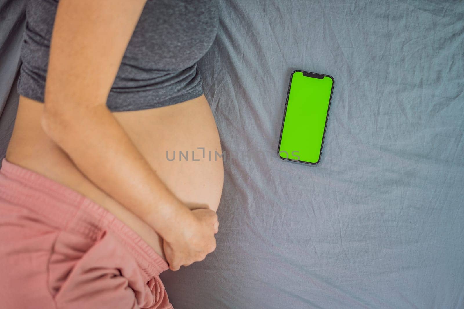 Pregnant girl with a smartphone. The concept of a negative impact on the unborn child in the womb. Violation of the nervous system of the child, reproductive.