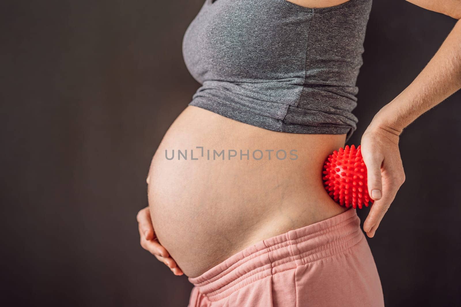 Self-massage with a massager for a pregnant woman.