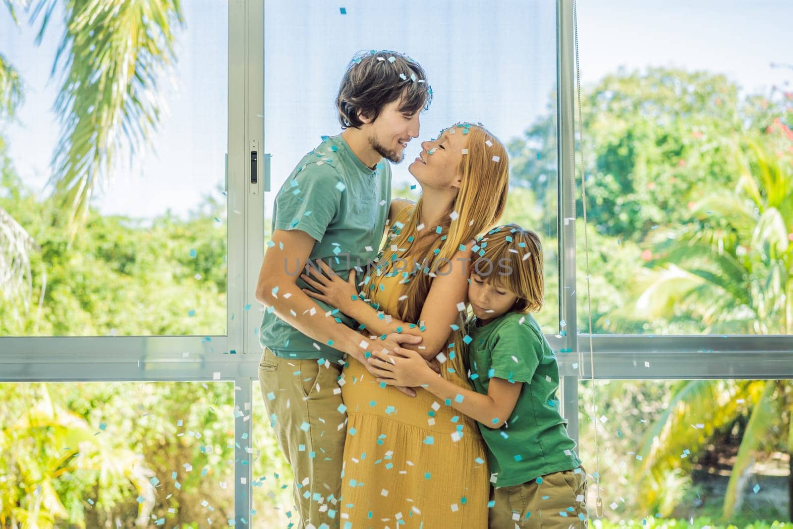 It's a boy. Expectant parents mother, father and their elder son are having a gender reveal party. A married the couple burst the balloon and the blue confetti flew out. Family, pregnancy and prenatal care concept.