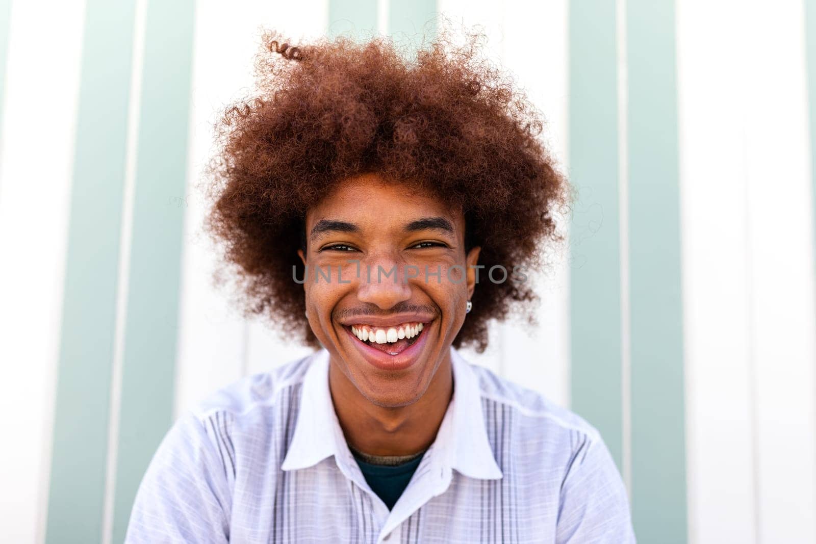 Headshot of happy African American Black young man smiling looking at camera. Summertime. by Hoverstock