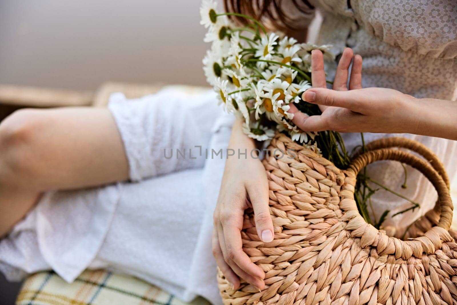 a woman gently touches the daisies lying in a wicker bag. photograph without a face by Vichizh