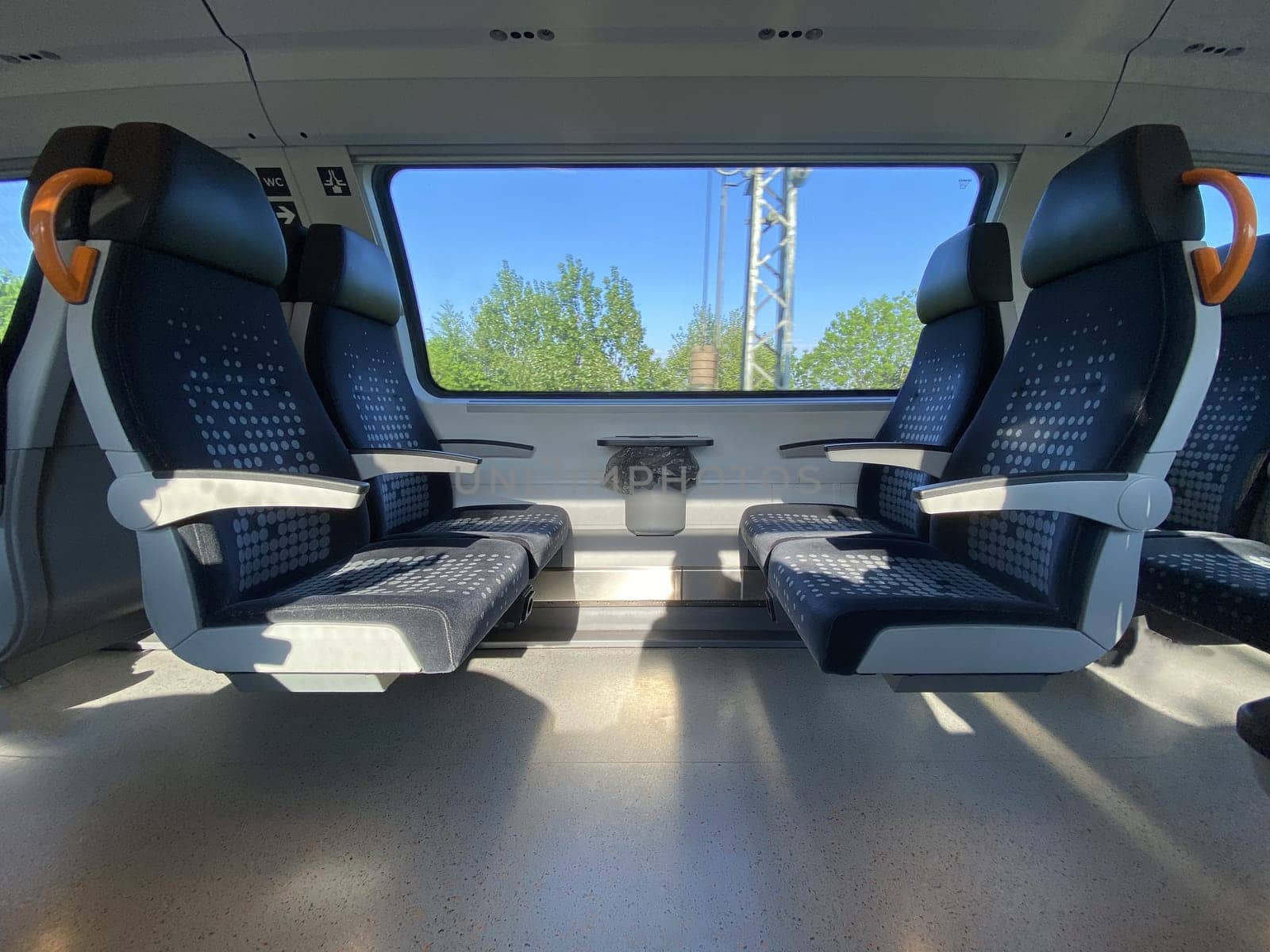 Empty cabin of a modern passenger train. Empty blue seats inside train cabin, corridor view, no people. Modern european economy class fast train interior.