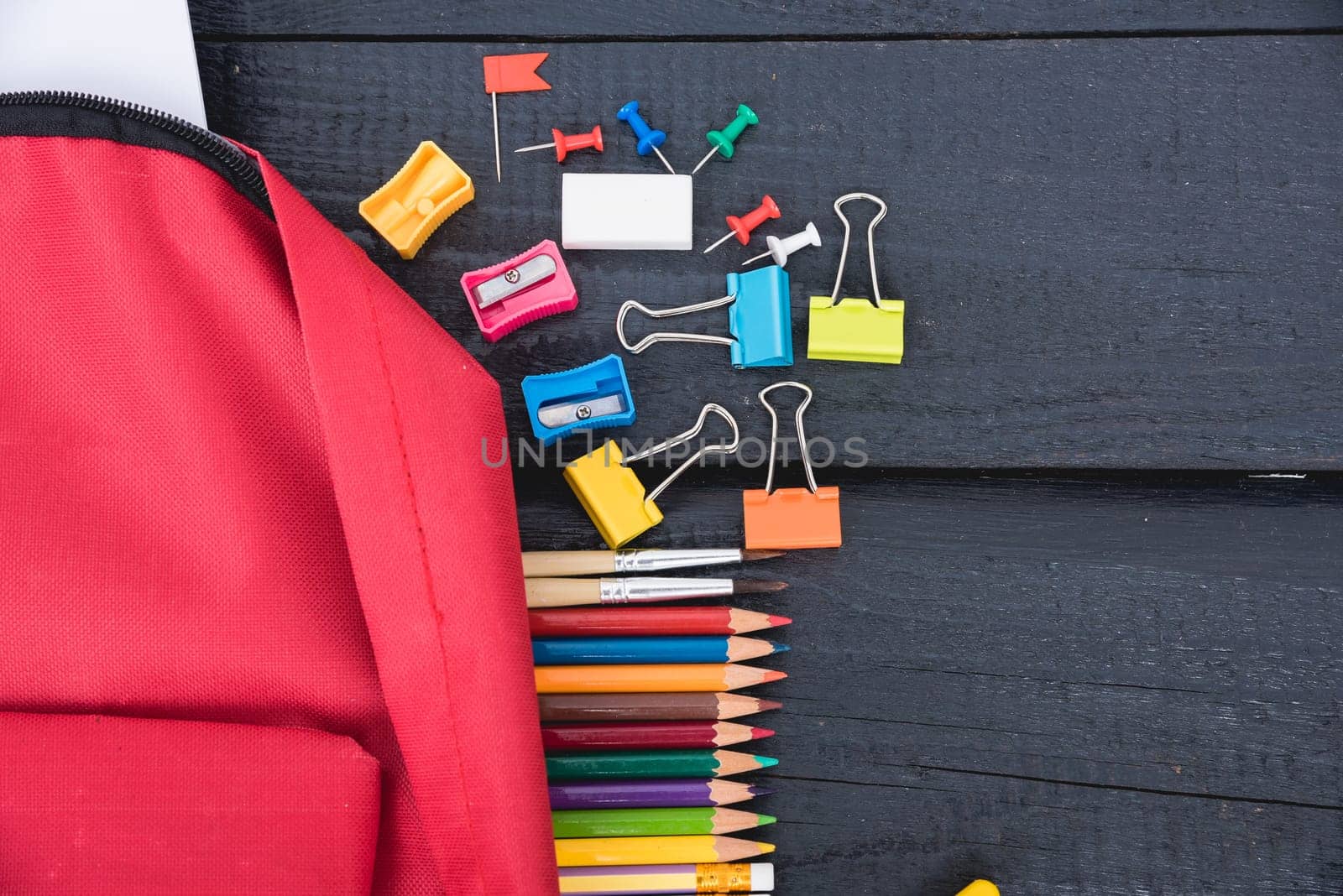 Top view flat lay of red school bag backpack and accessories tools for children education on black wood background, Back to school concept and have copy space for use