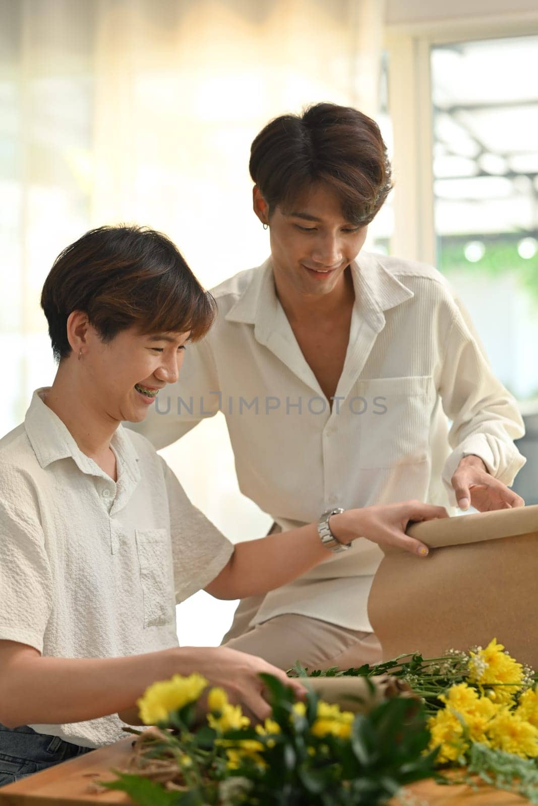 Beautiful young gay couple having fun while making bouquet, decorations and arrangements flower. Gay couples and lifestyle.