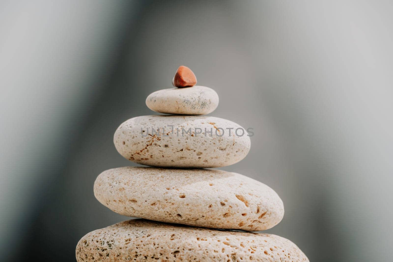 balanced rock pyramid stands tall on sea pebble beach. Selective focus highlights zen stones on the beach, evoking feelings of calm, harmony, and balance. Perfect for meditation or spa concepts. by panophotograph