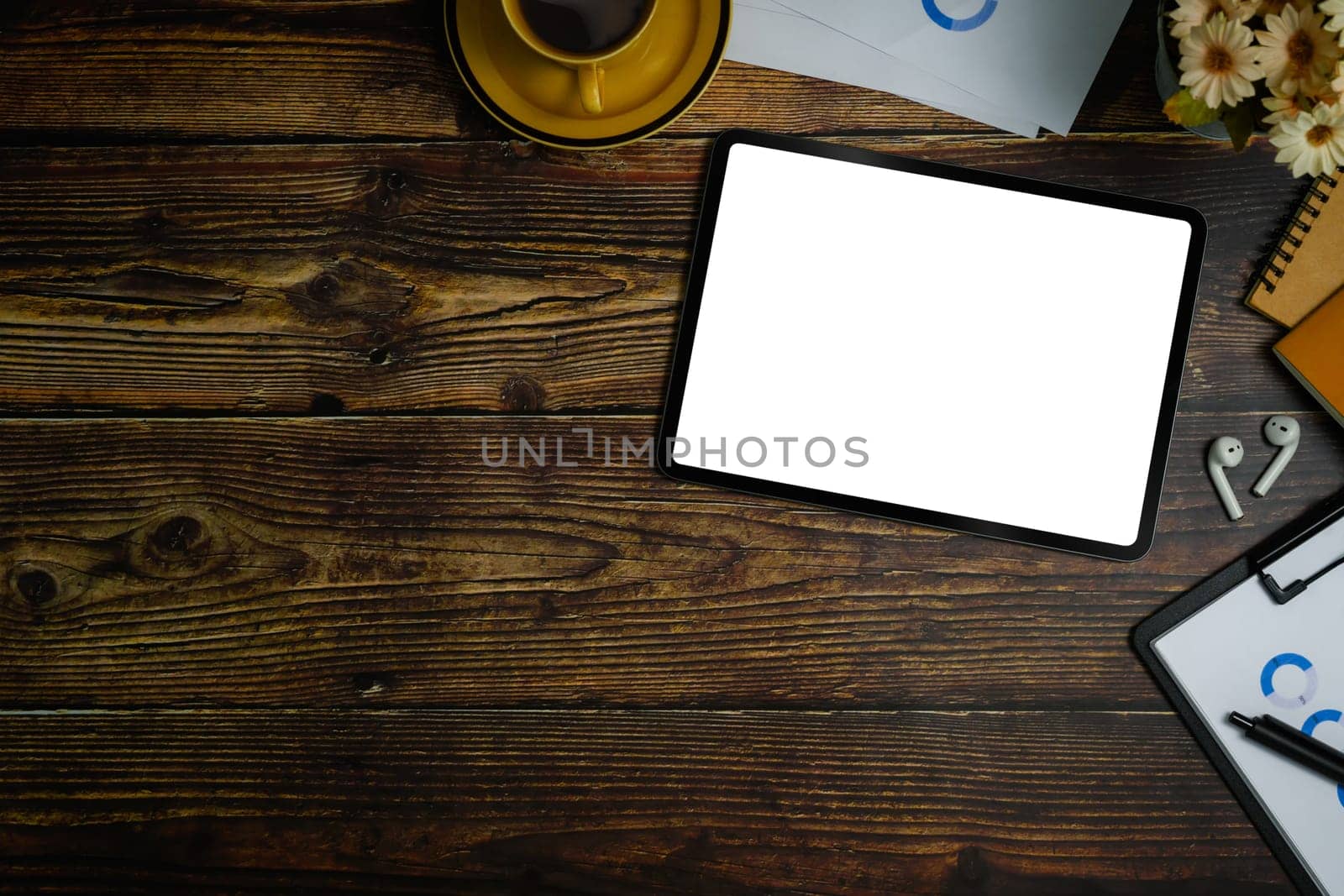 Flat lay, top view of digital tablet with white empty screen, financial document and coffee cup on wooden office desk.