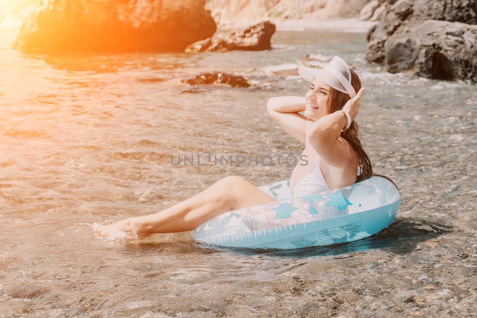 Woman summer sea. Happy woman swimming with inflatable donut on the beach in summer sunny day, surrounded by volcanic mountains. Summer vacation concept