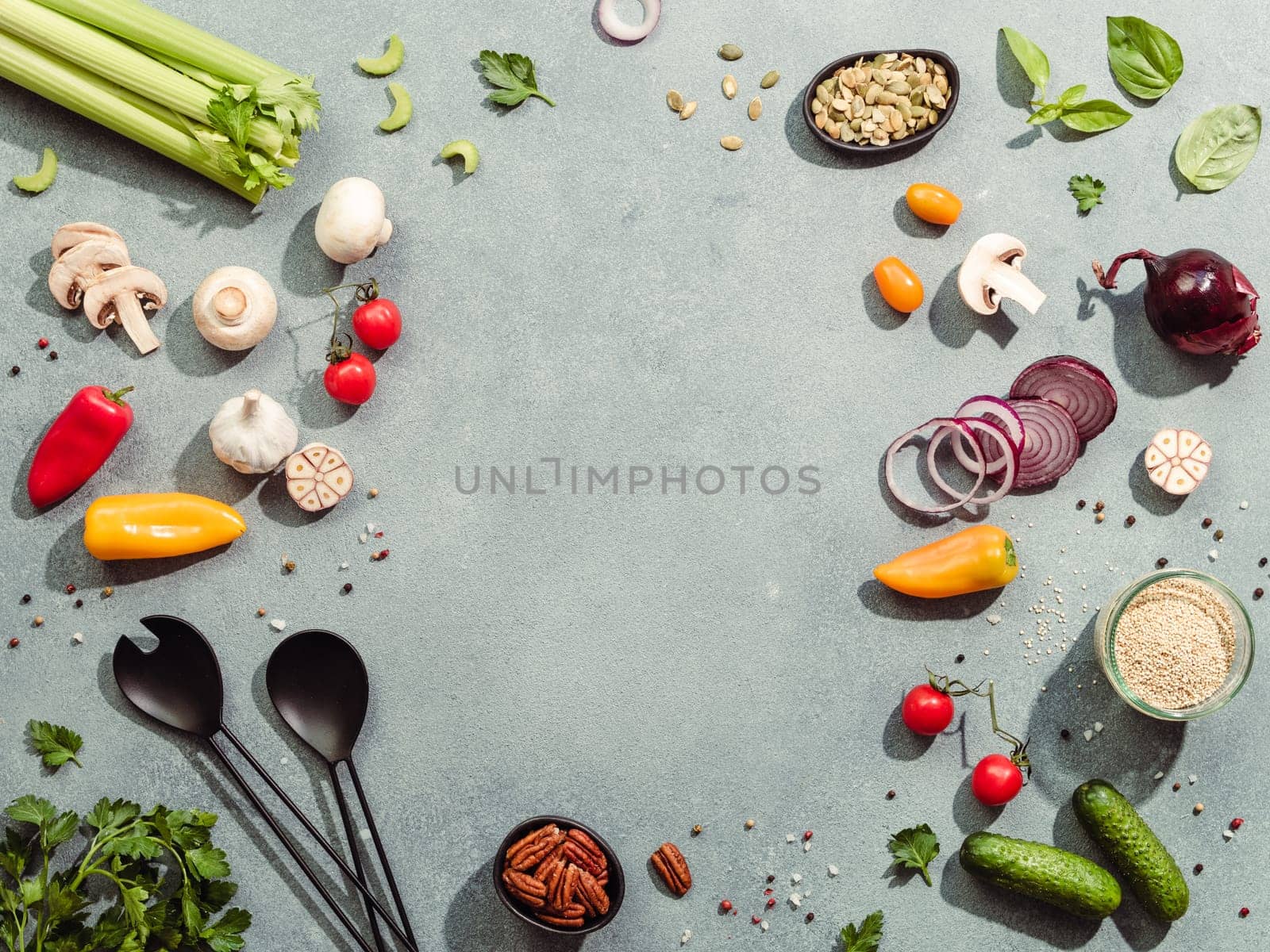 Food ingredients, salad serving utensils with copy space for text or design in center. Various of vegetarian cooking ingredients on gray background. Top view or flat lay