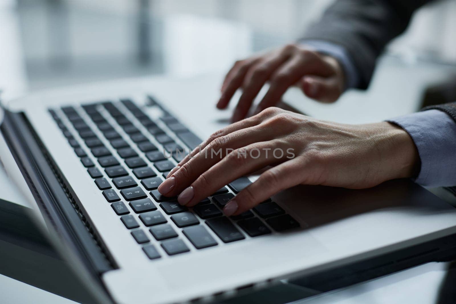 man's hands typing on laptop keyboard in interior