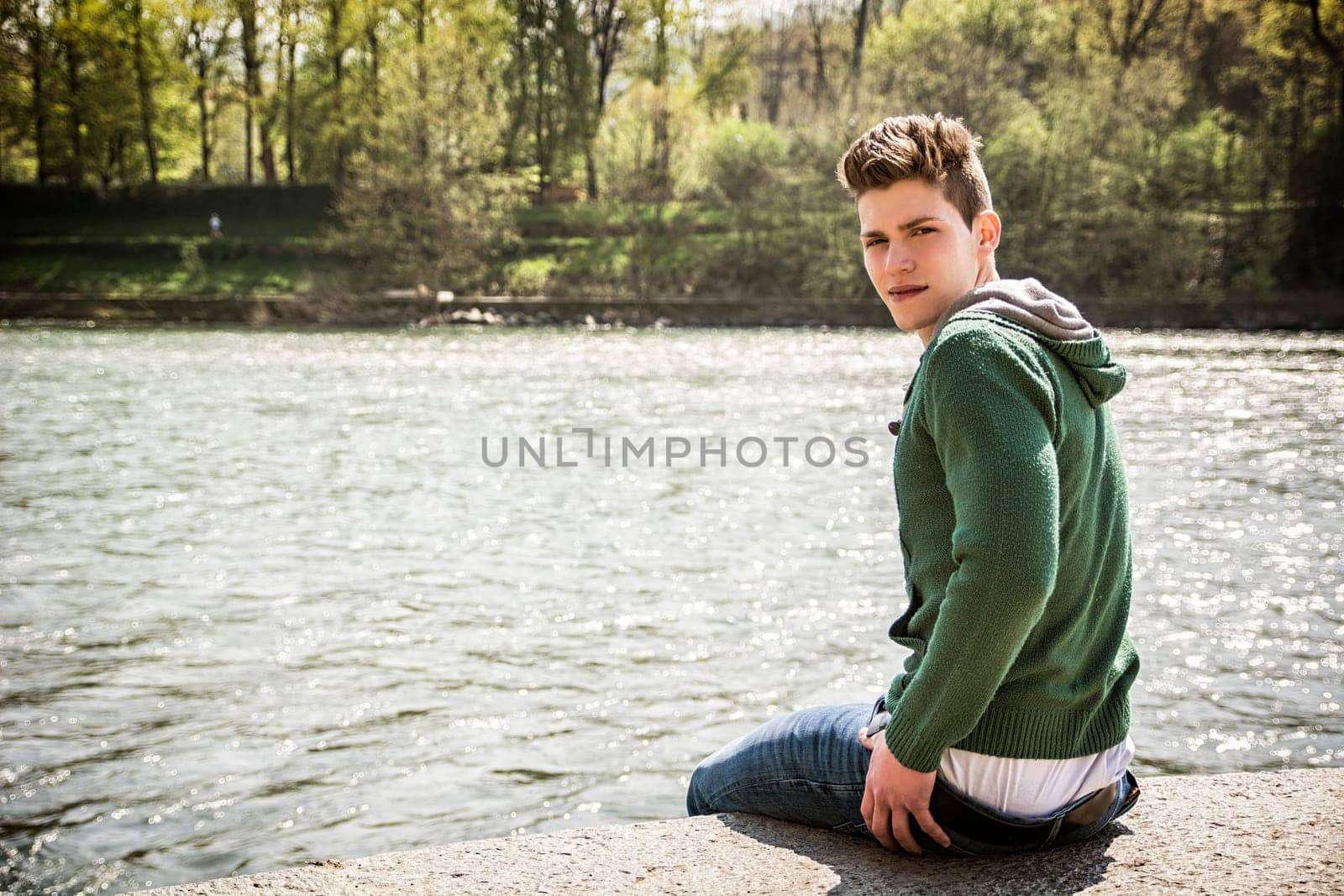 Contemplative young man sitting beside river in Turin by artofphoto