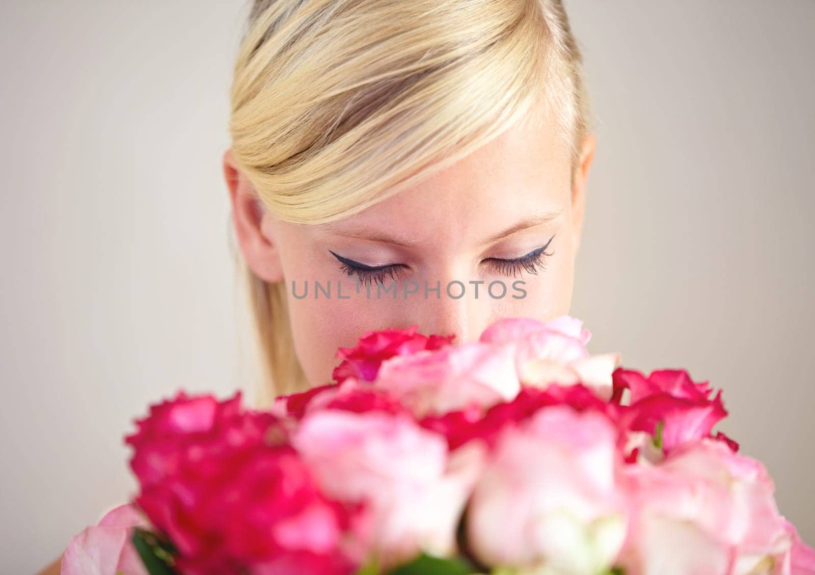 Smelling, romance and woman with flowers as a gift isolated on a grey studio background. Surprise, romantic and girl with a bouquet of roses for valentines day with a natural, floral present.