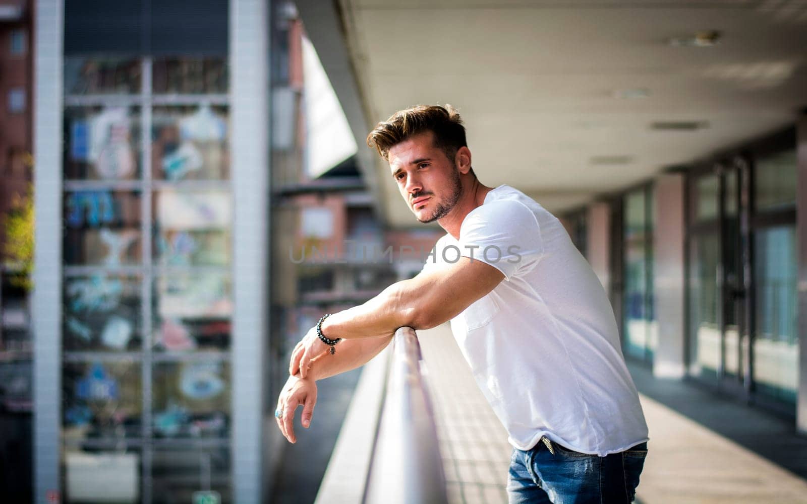 Handsome fit man in white t-shirt outdoor in city setting, looking away