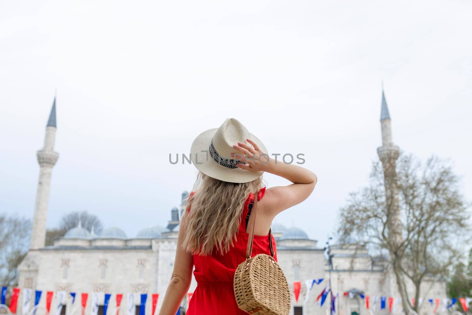 A beautiful travel blogger girl in a long red dress and a straw hat is photographed at the ancient sights in Istanbul in Turkey.