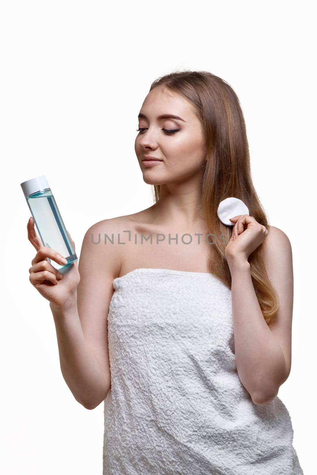 beautiful woman holding bottle with tonic, cleaning skin with cotton pad. Beauty and skin care concept