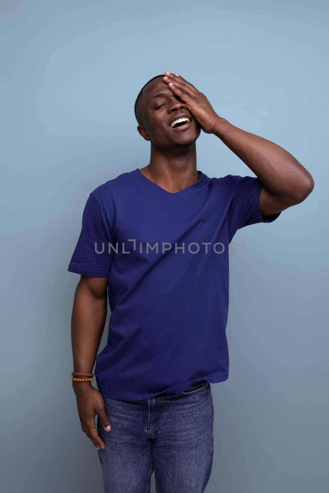 cute modest young african man in blue t-shirt on blue background.