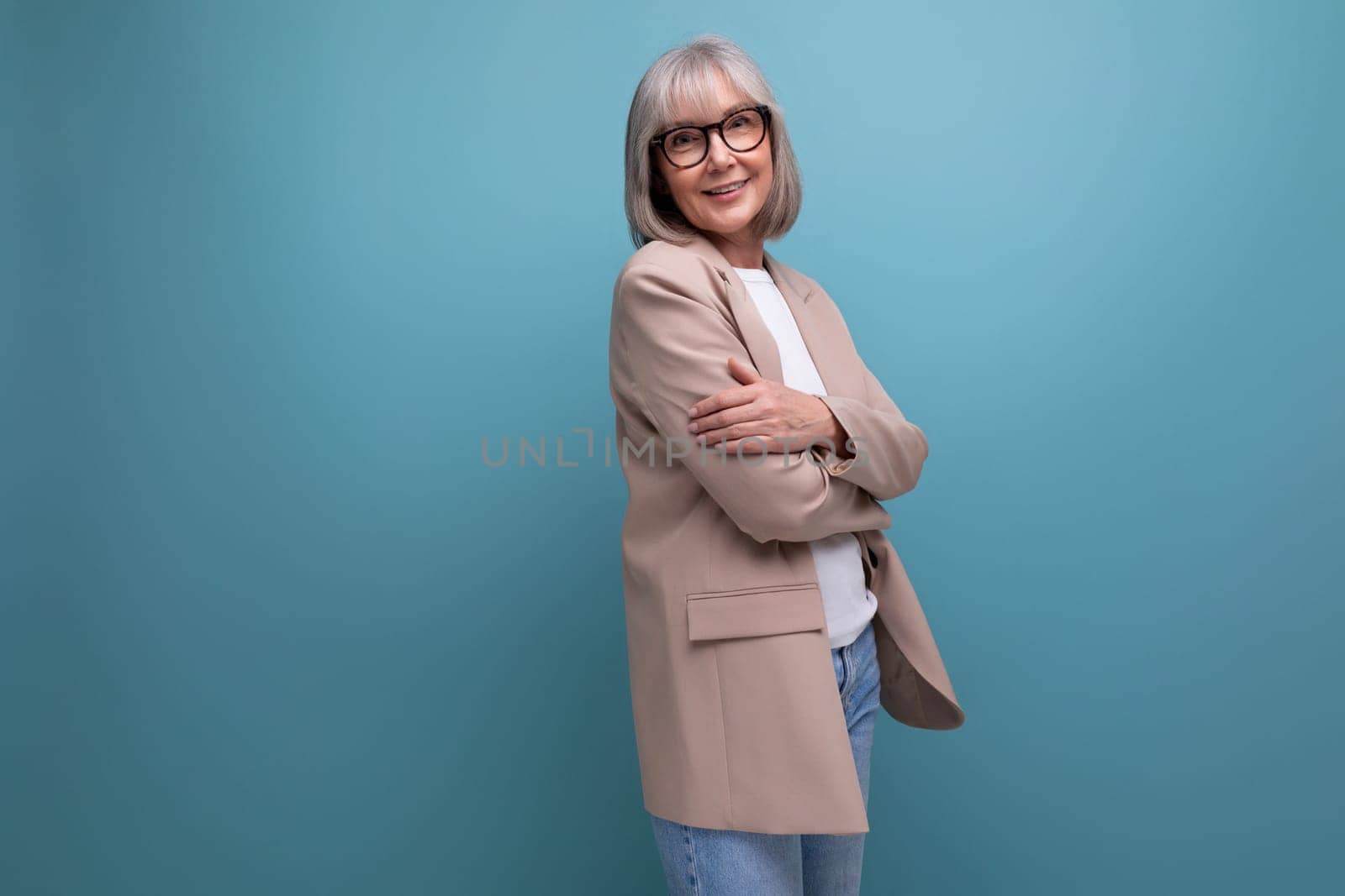successful middle-aged woman grandmother with gray hair in a jacket on a bright background with copy space.